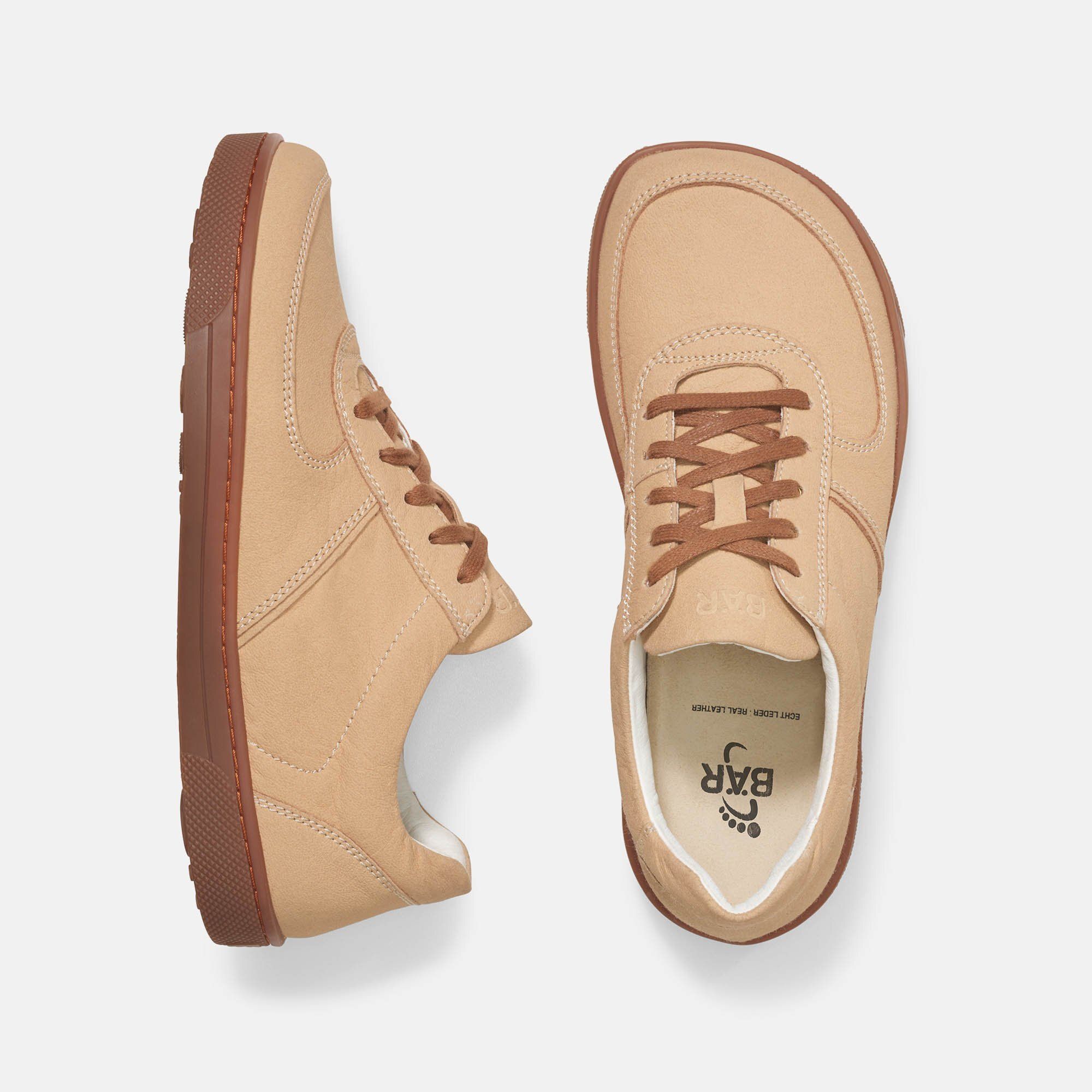 Zwei Schuhe, Draufsicht. Beigefarbene Schnürschuhe mit braunen Sohlen. Innensohle mit Logo.