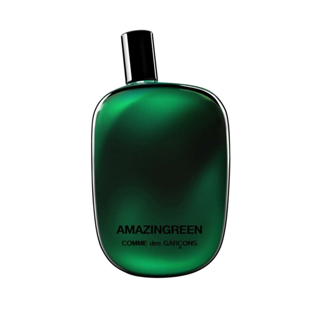 Grüne Flasche mit schwarzem Verschluss. Aufschrift: AMAZINGREEN, COMME des GARÇONS. Abgerundete Form.