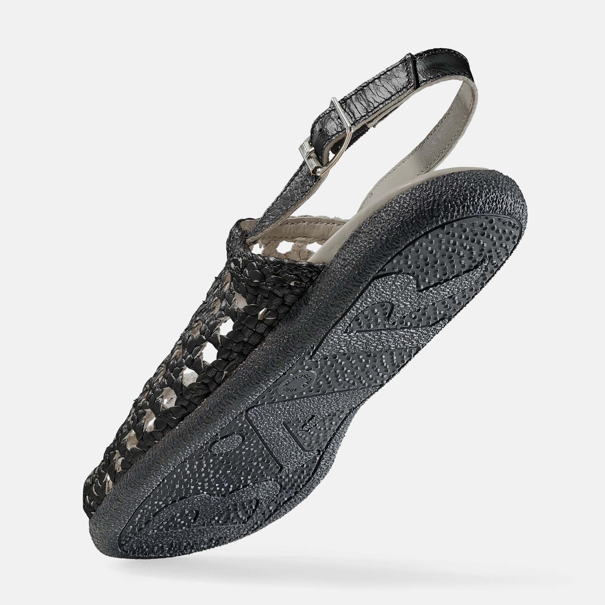 Schwarze Sandale, Unteransicht. Geflochtenes Obermaterial, Riemen mit Schnalle. Profilierte Sohle.