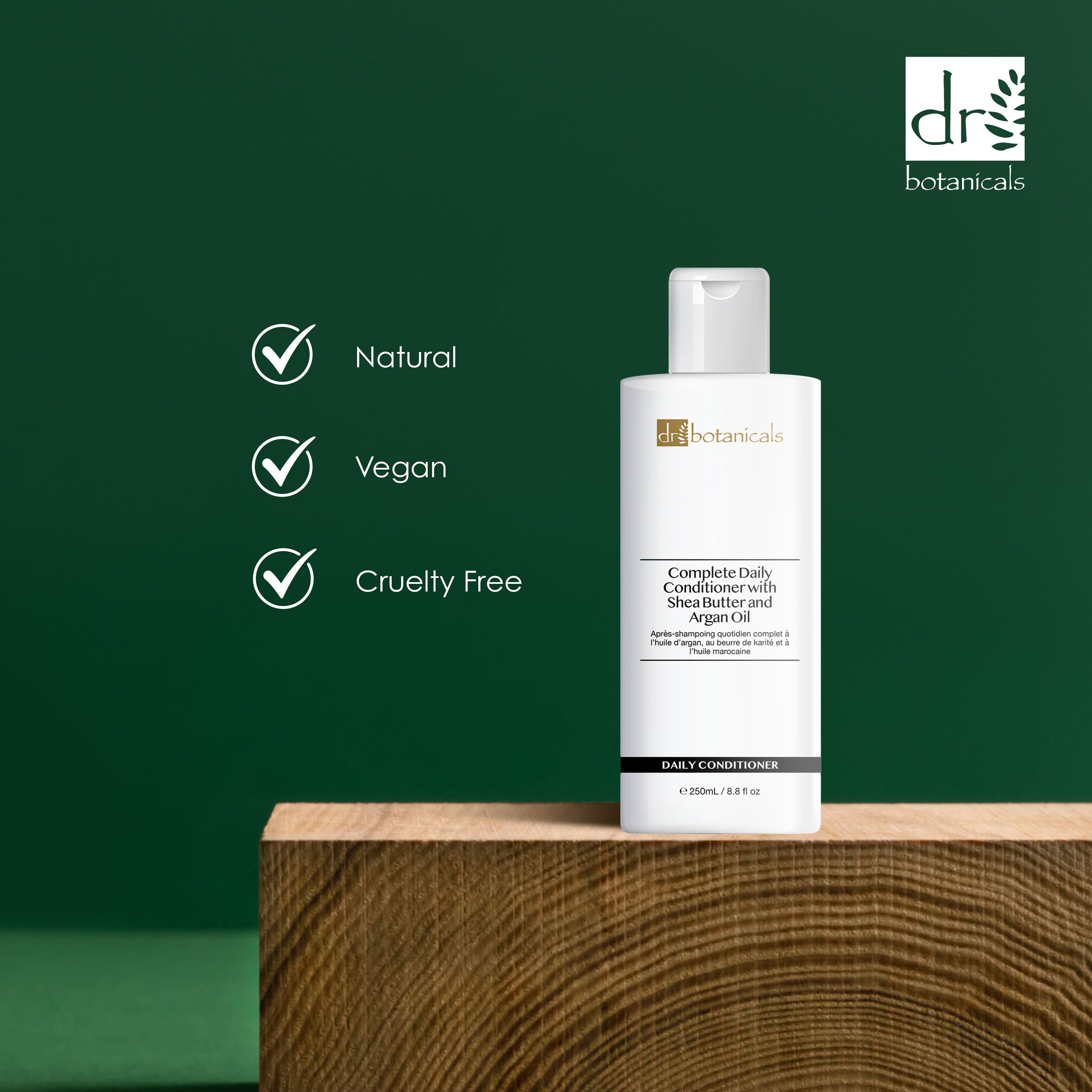 Flasche Conditioner auf Holzblock. Text: Complete Daily Conditioner with Shea Butter and Argan Oil. Marke: dr. botanicals. Text: Natural, Vegan, Cruelty Free.