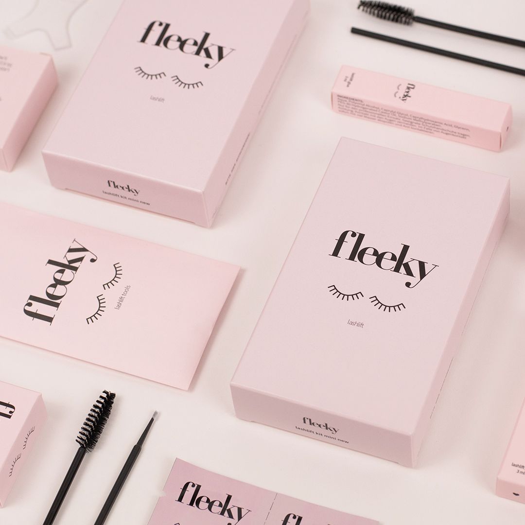 Fleeky Lashlift Kit. Rosa Verpackungen und Zubehör. Mehrere Kartons, Lotionen und Applikatoren. Logo und Augen-Illustration auf den Verpackungen.