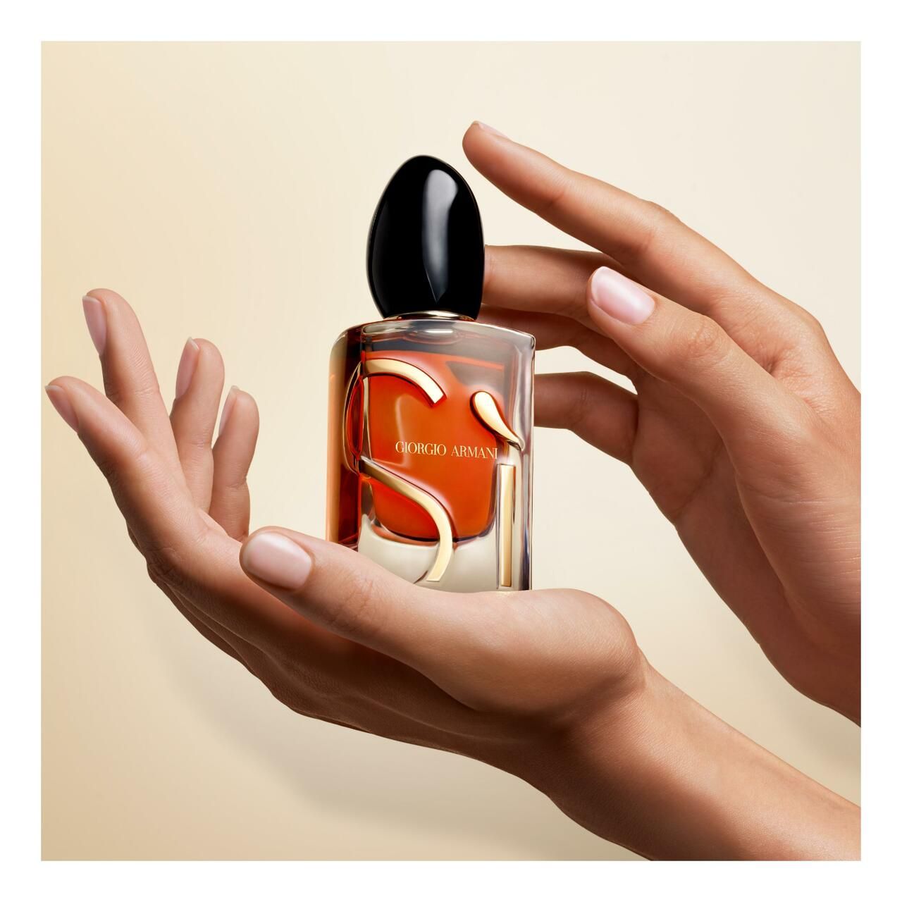 Hände halten einen Giorgio Armani Si Parfum Flakon.