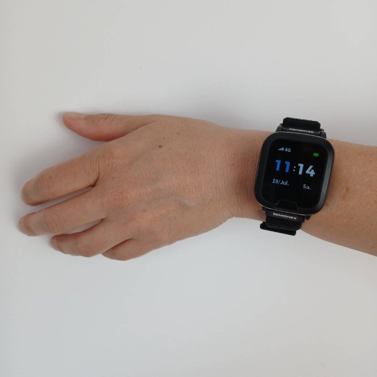 Schwarzes Notruf-Armband am Handgelenk, zeigt Uhrzeit und Datum.
