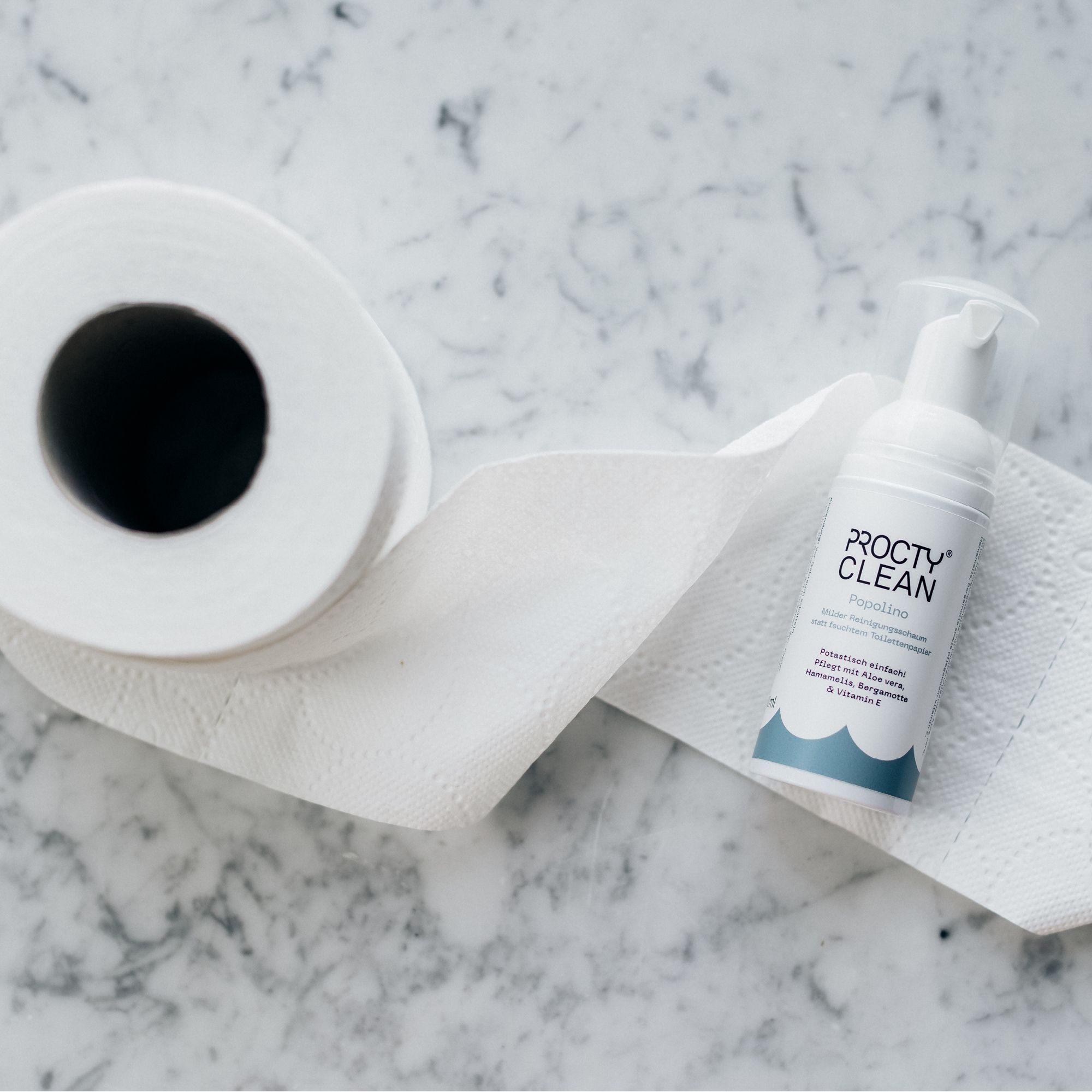 Flasche auf Toilettenpapierrolle. Flasche: ProctyClean Popolino. Blaue Wellen am Boden.