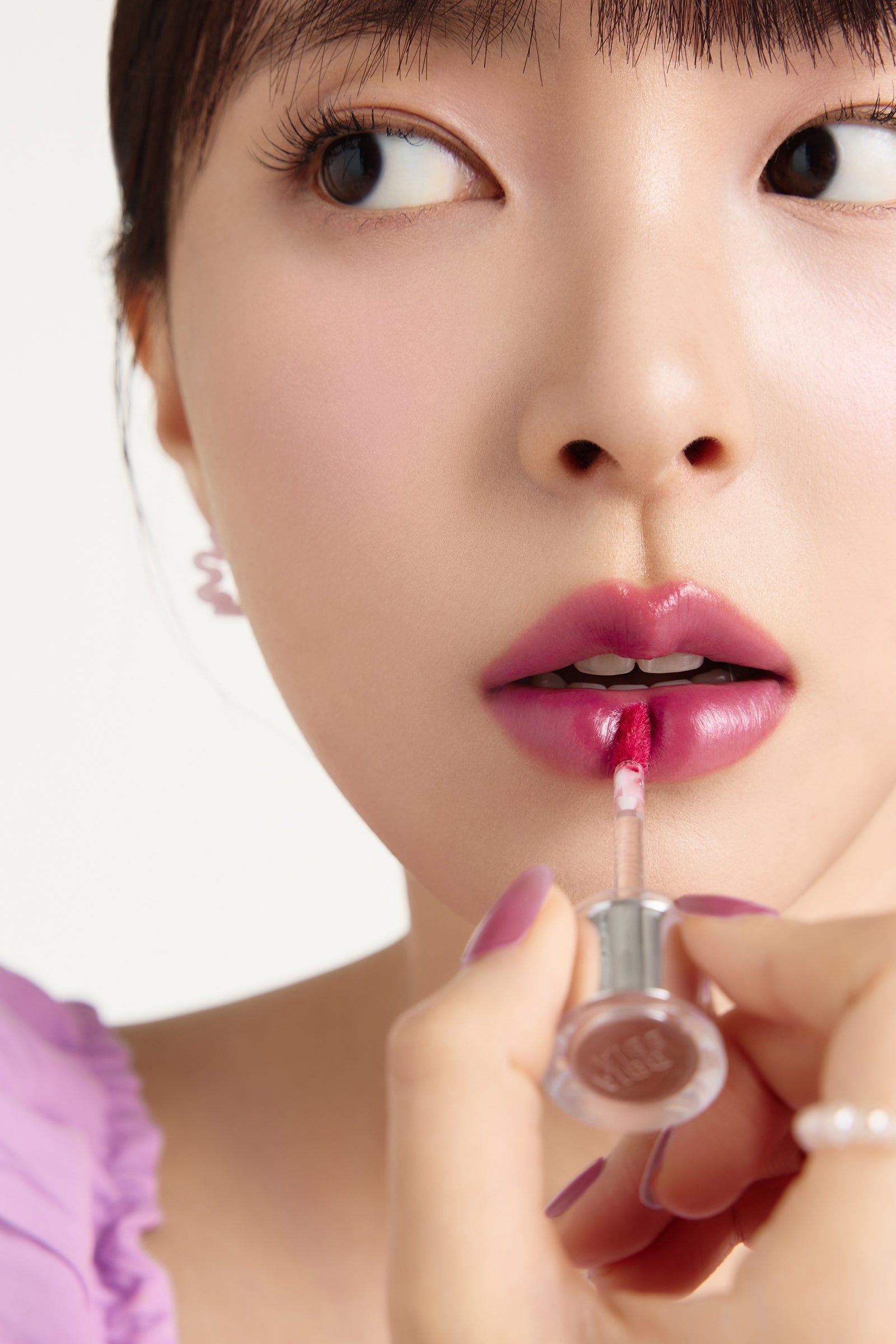 Nahaufnahme einer Frau, die Lippenstift aufträgt. BBIA L'eau Tint 03 Lilac L'eau.
