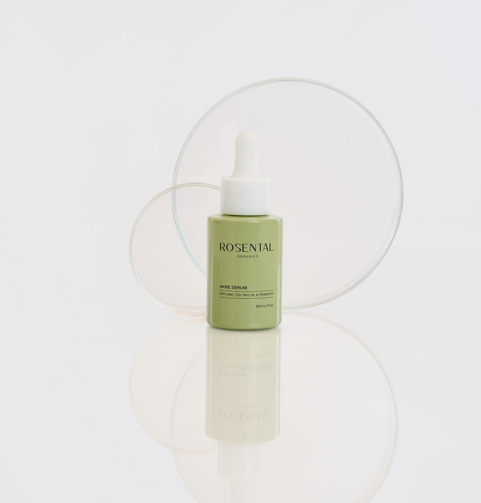 Grüne Flasche mit Pipette, vor transparenten Kreisen. Produktname und Marke sichtbar.