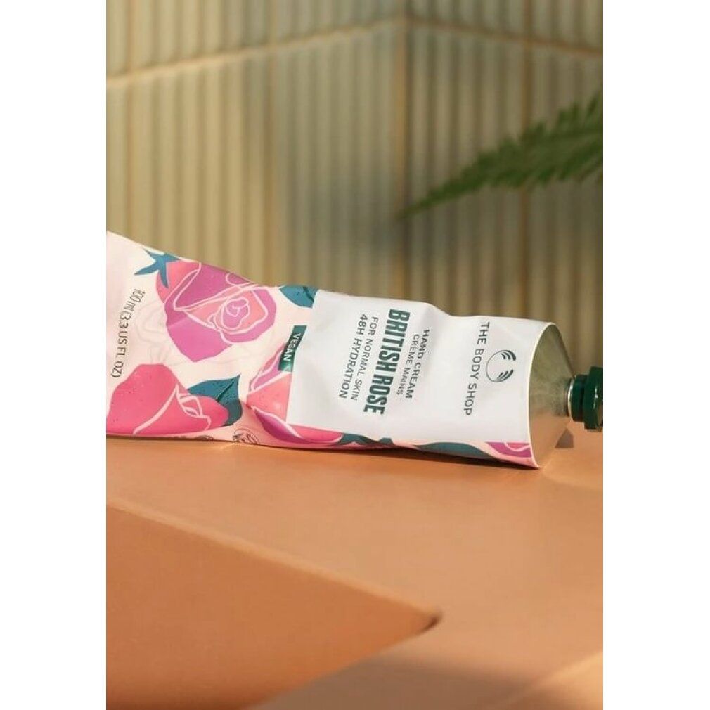 Zusammengeknickte Creme-Tube "The Body Shop", "British Rose". Auf rosa Oberfläche. Rosenmuster.