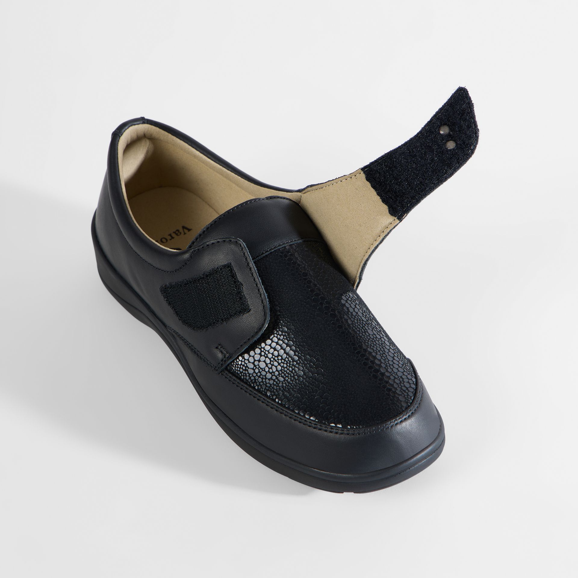 Schwarzer Damenschuh mit Klettverschluss. Nahaufnahme des offenen Schuhs.