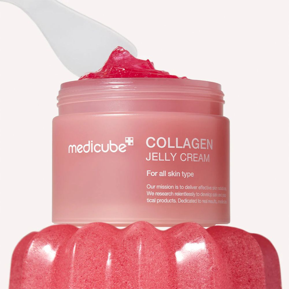 Medicube Collagen Jelly Cream in einem rosa Tiegel mit Spatel, der die rosa Creme entnimmt.