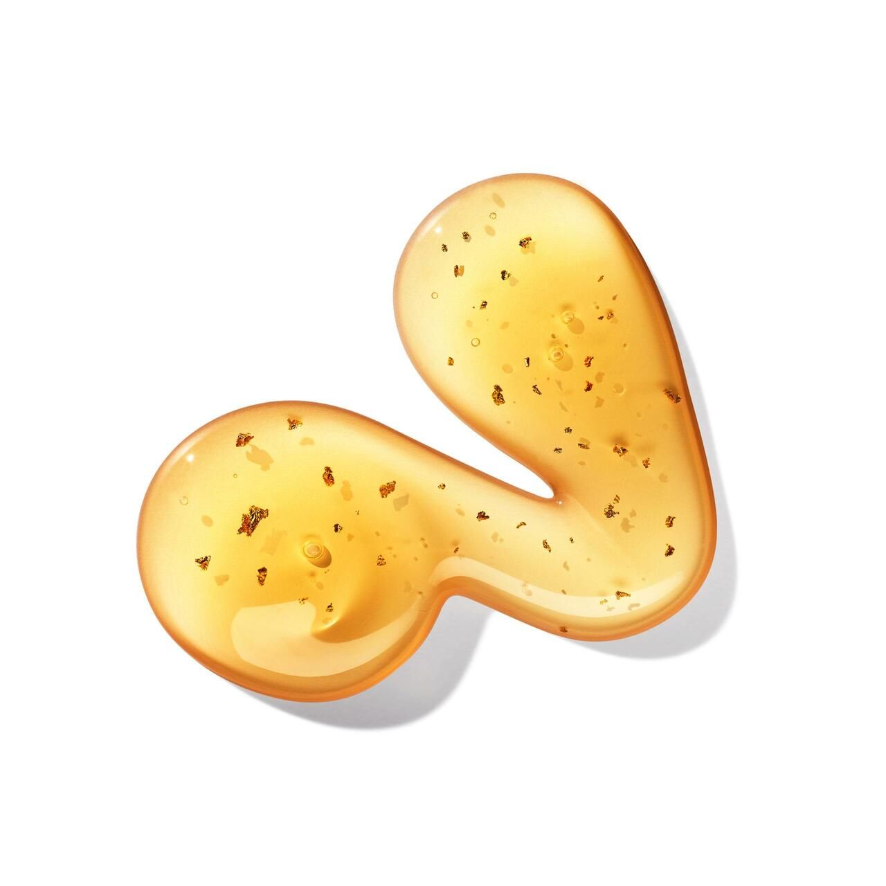 Gel-Tropfen mit goldenen Partikeln. Geformt wie eine geschwungene Linie. Auf weißem Hintergrund.