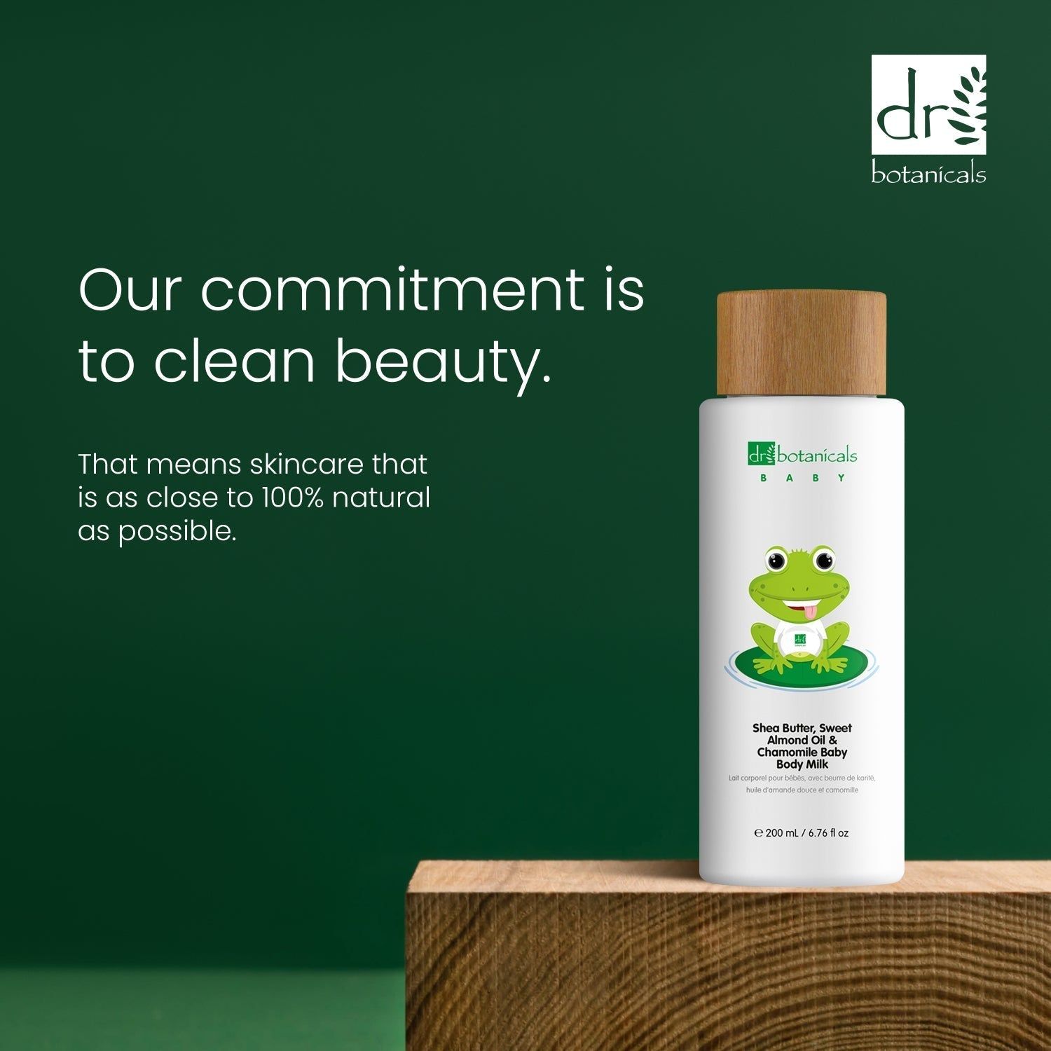 Produktflasche mit Holzdeckel. Text: 'Our commitment is to clean beauty'. Marke: Dr Botanicals Baby. Hintergrund: Holzblock, grün.
