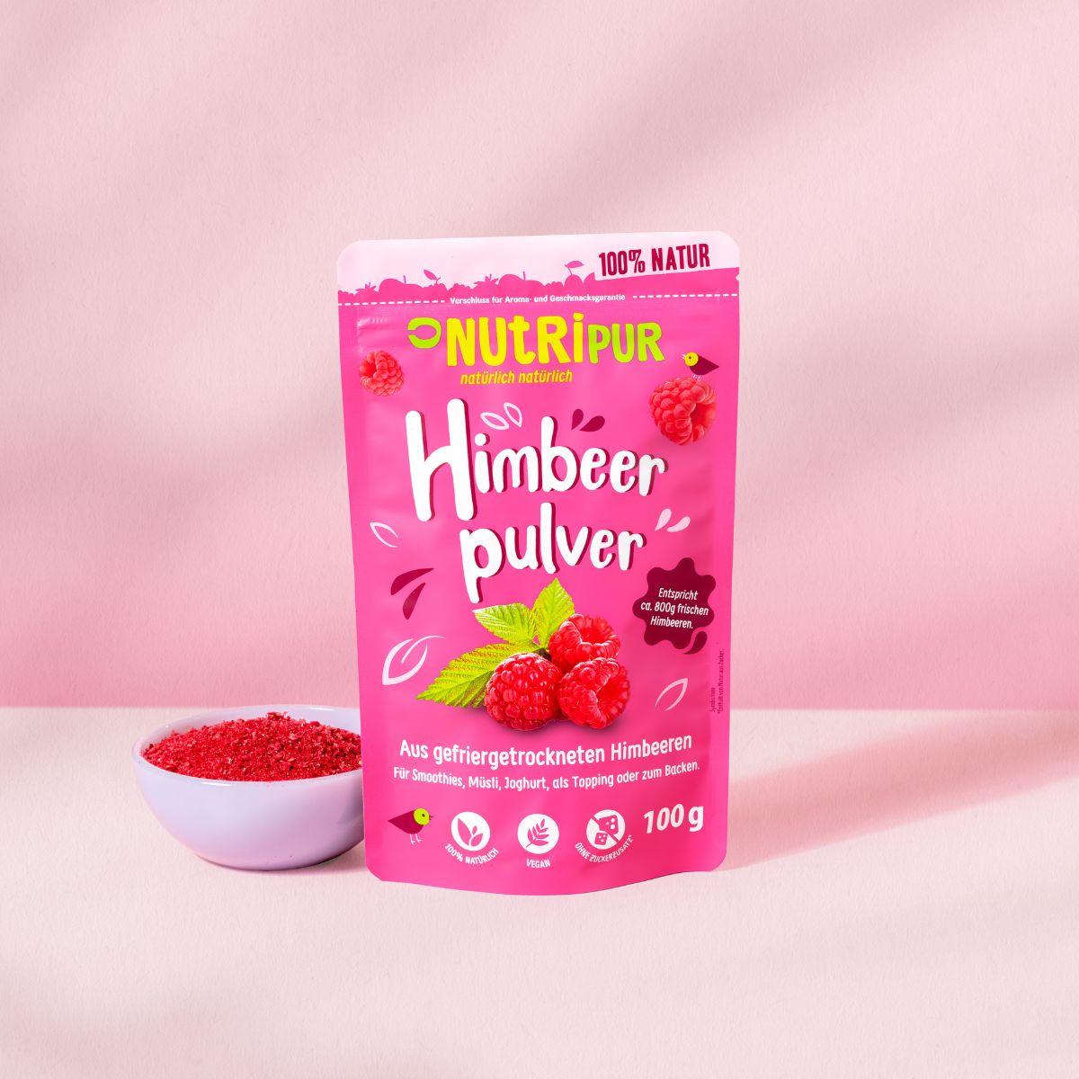 Rosa Beutel mit Himbeerpulver, Himbeeren und Blättern. Aufschrift: NutriPur Himbeerpulver. 100g.