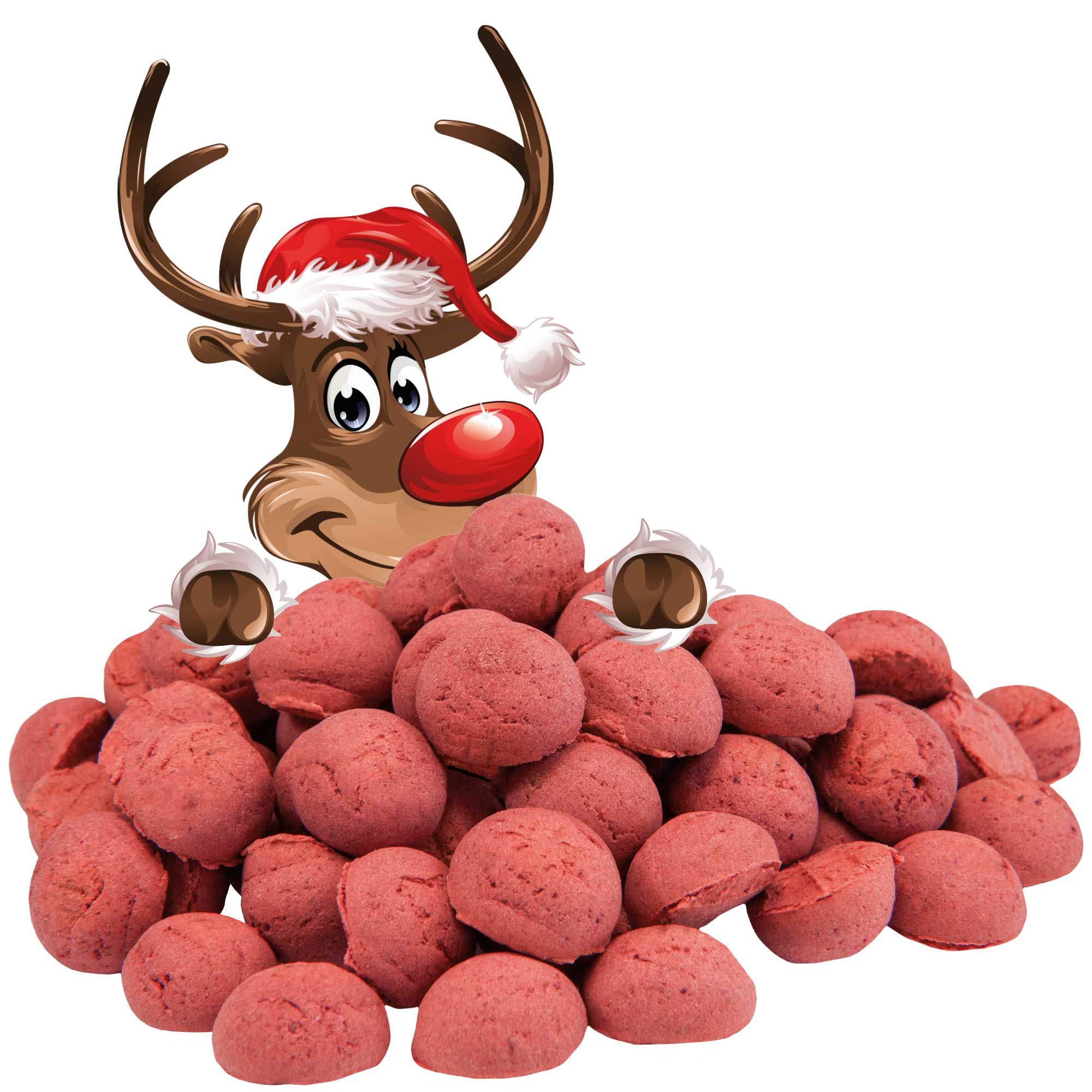 Hundekekse, rot, in Haufen. Ein Rentier mit Weihnachtsmütze blickt über die Kekse.