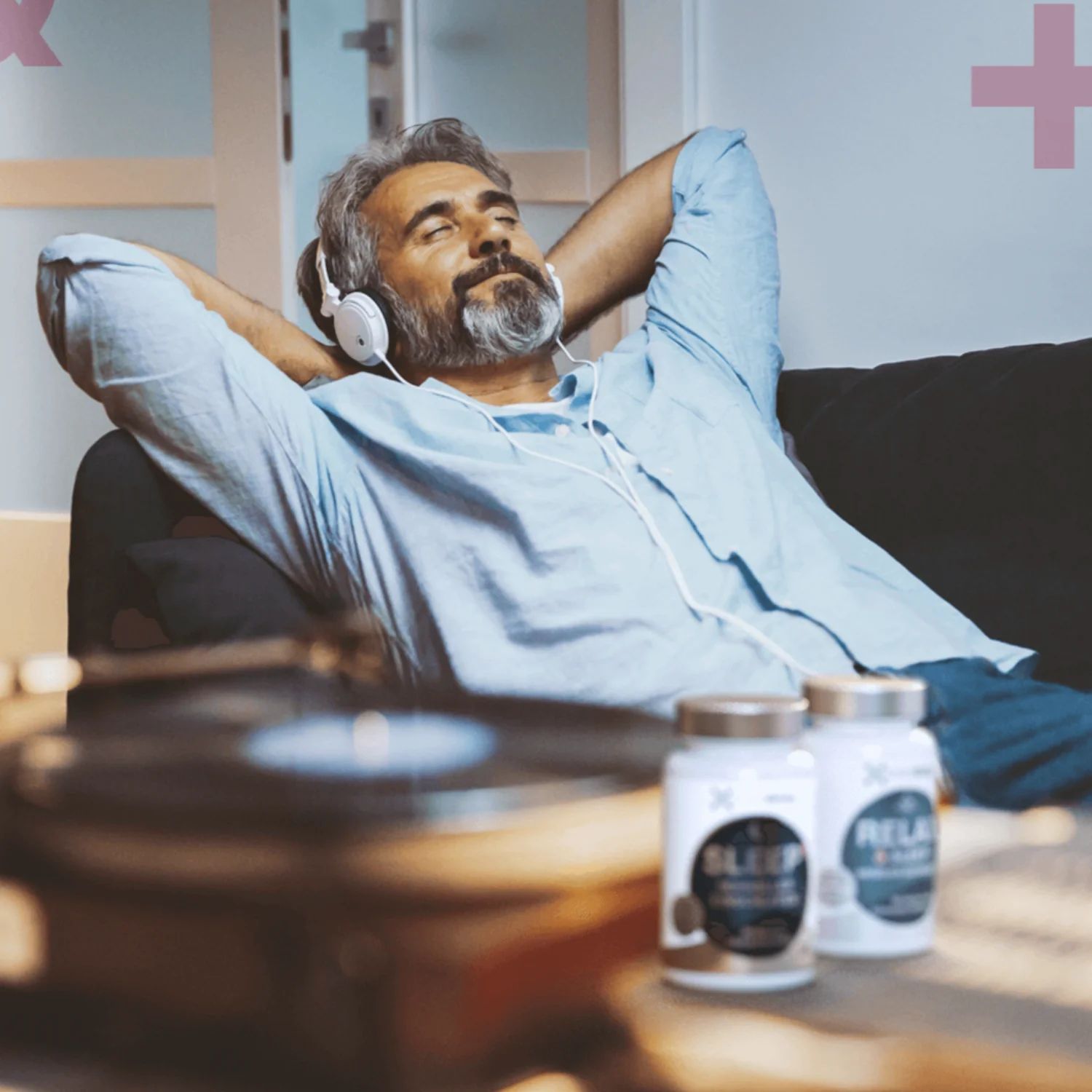 Mann mit Kopfhörern auf dem Sofa. Zwei Flaschen smartsleep SLEEP+ auf dem Tisch. Aufschrift: SLEEP+.