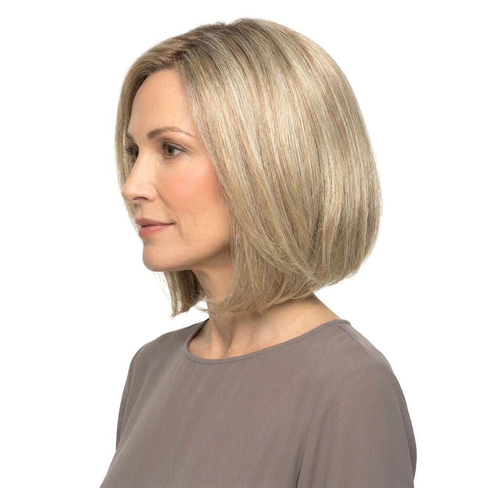 Blonde Perücke mit kurzem, gestuftem Schnitt. Die Frau trägt ein braunes Oberteil. Seitenansicht.
