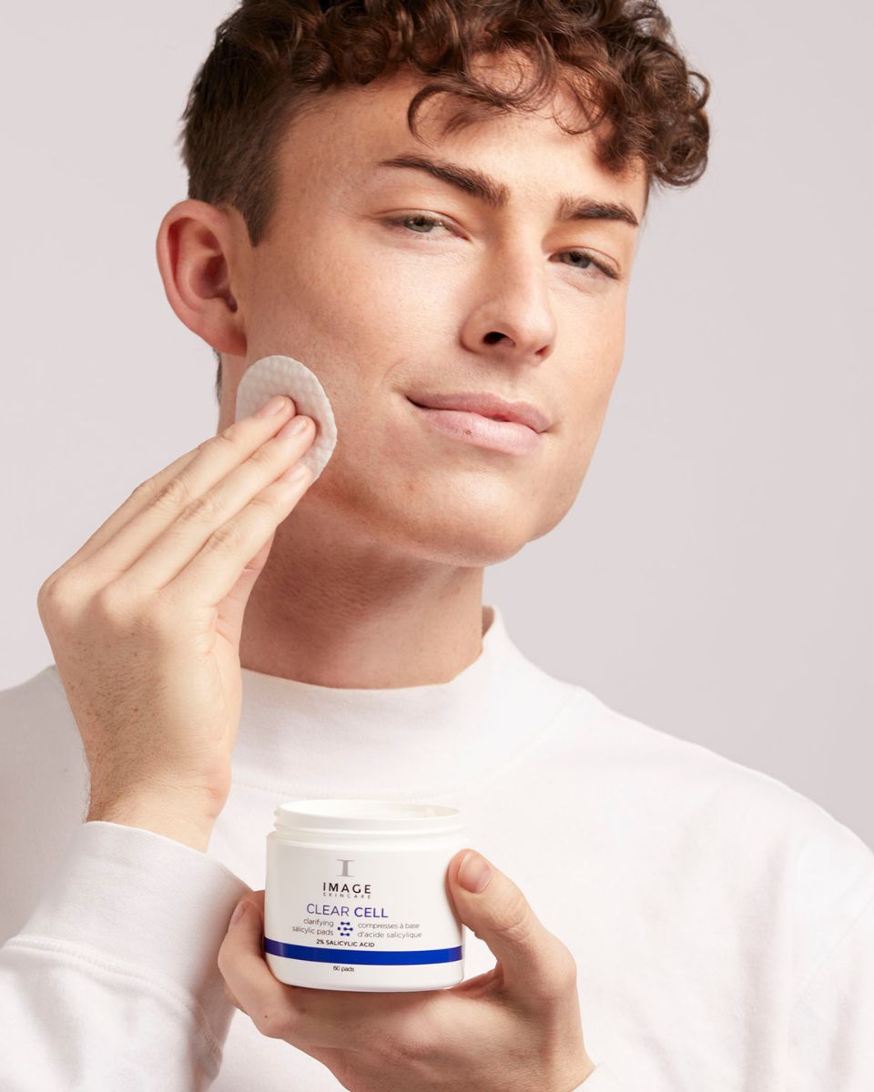 Mann verwendet ein Pad. Dose mit Aufschrift: IMAGE SKINCARE CLEAR CELL, klärende Salicylsäure-Pads. 60 Pads.