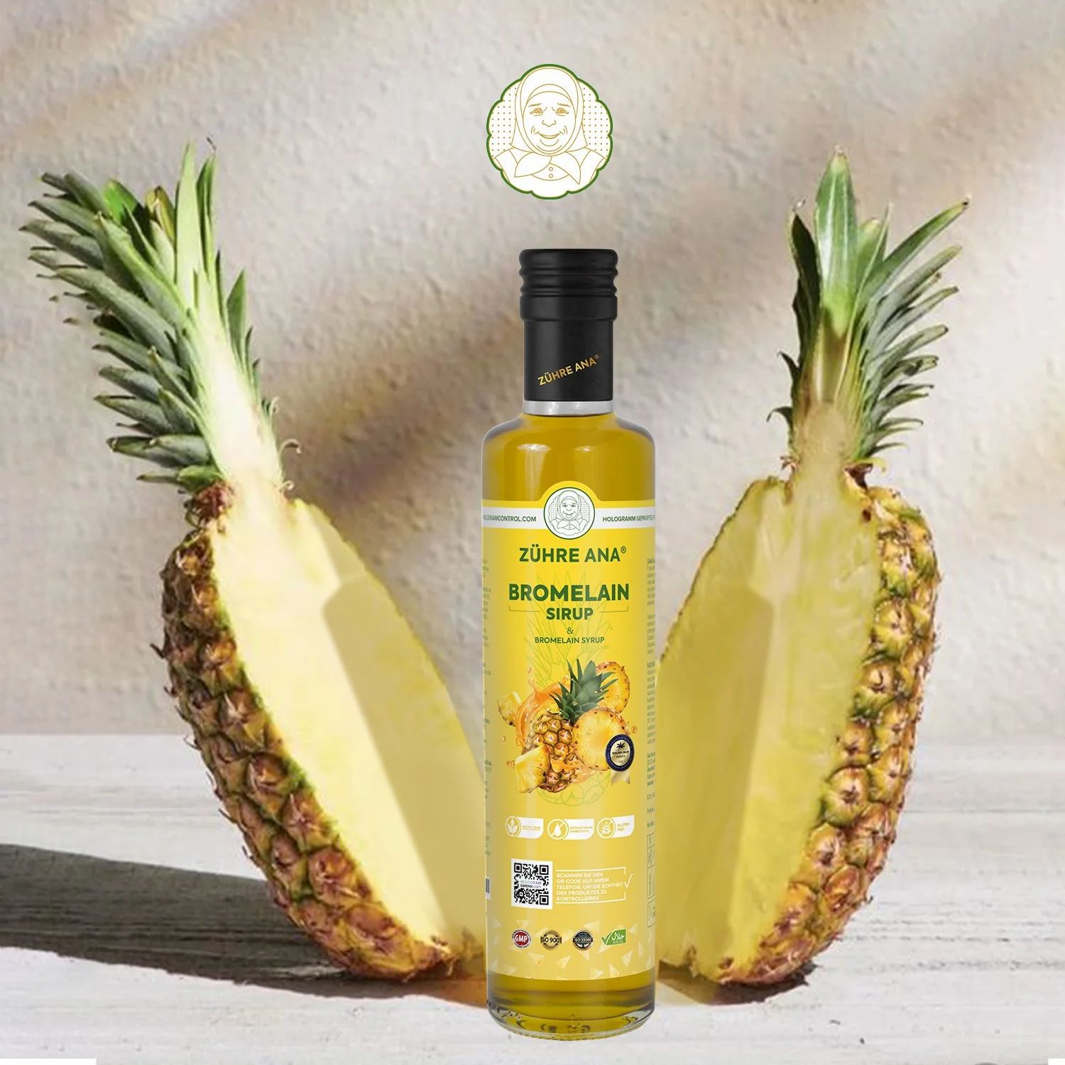 Gelbe Flasche mit schwarzem Deckel. Aufschrift: Zühre Ana Bromelain Sirup. Daneben eine halbierte Ananas.