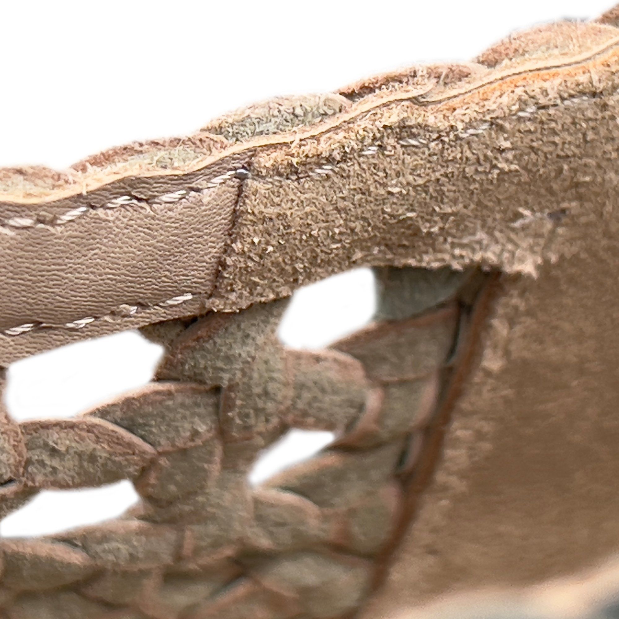 Nahaufnahme des Schuhmaterials. Gewebtes, braunes Leder mit sichtbaren Nähten.