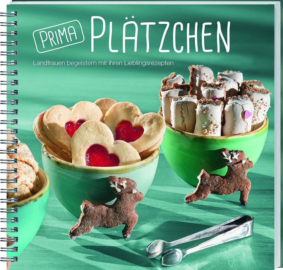 Kochbuch "Prima Plätzchen" mit Keksen in Schalen. Herzförmige Kekse mit roter Füllung, braune Rentierkekse und Zangen.