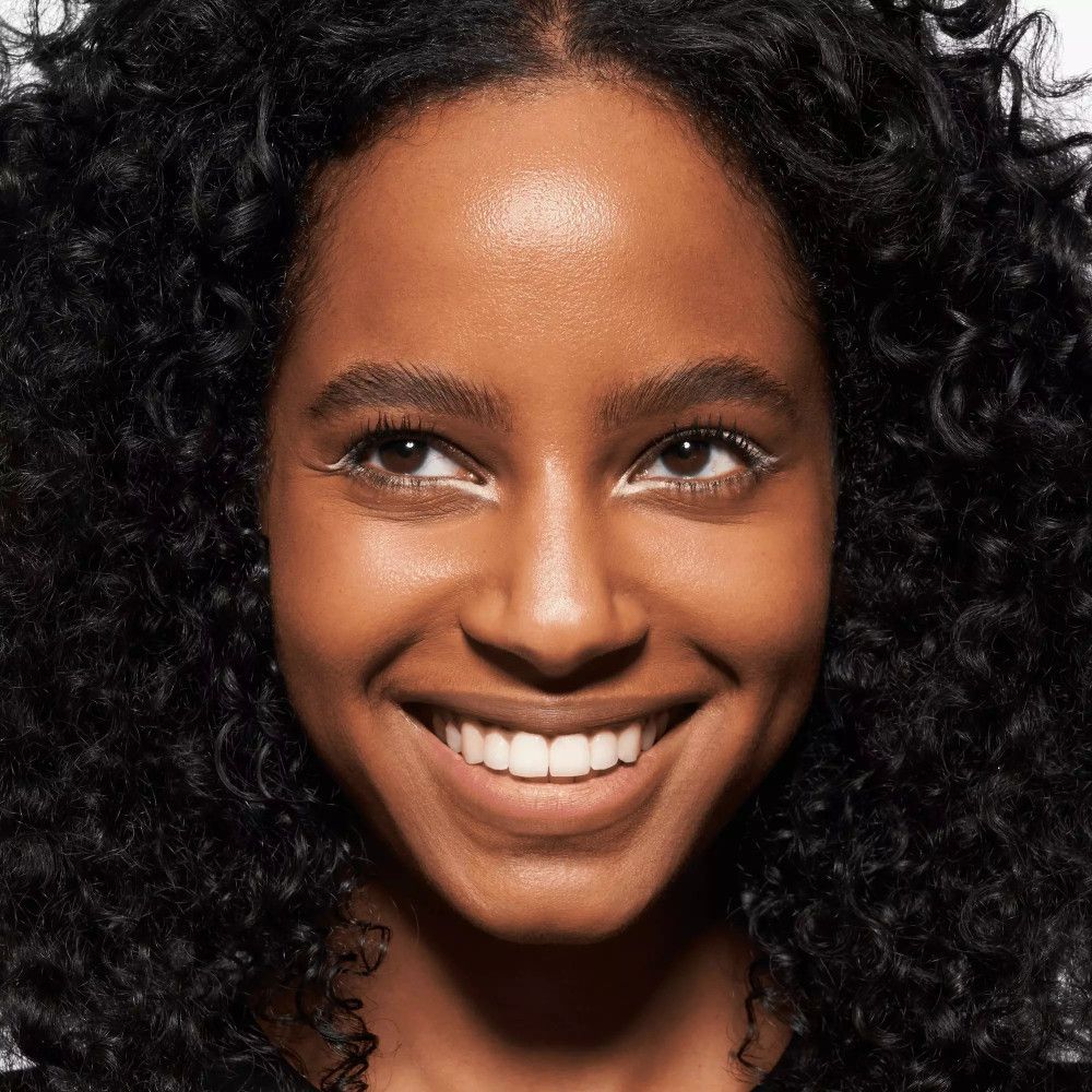 Frau mit dunklen Locken, weißen Kajal auf den Augen.