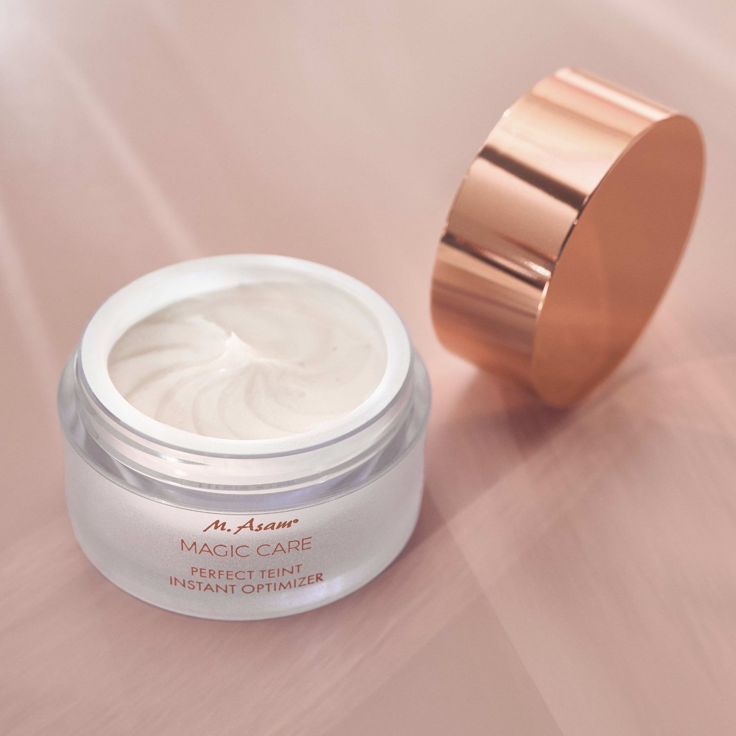 Vasetto di crema con coperchio aperto. Testo: M. Asam MAGIC CARE PERFECT TEINT INSTANT OPTIMIZER. Crema visibile.