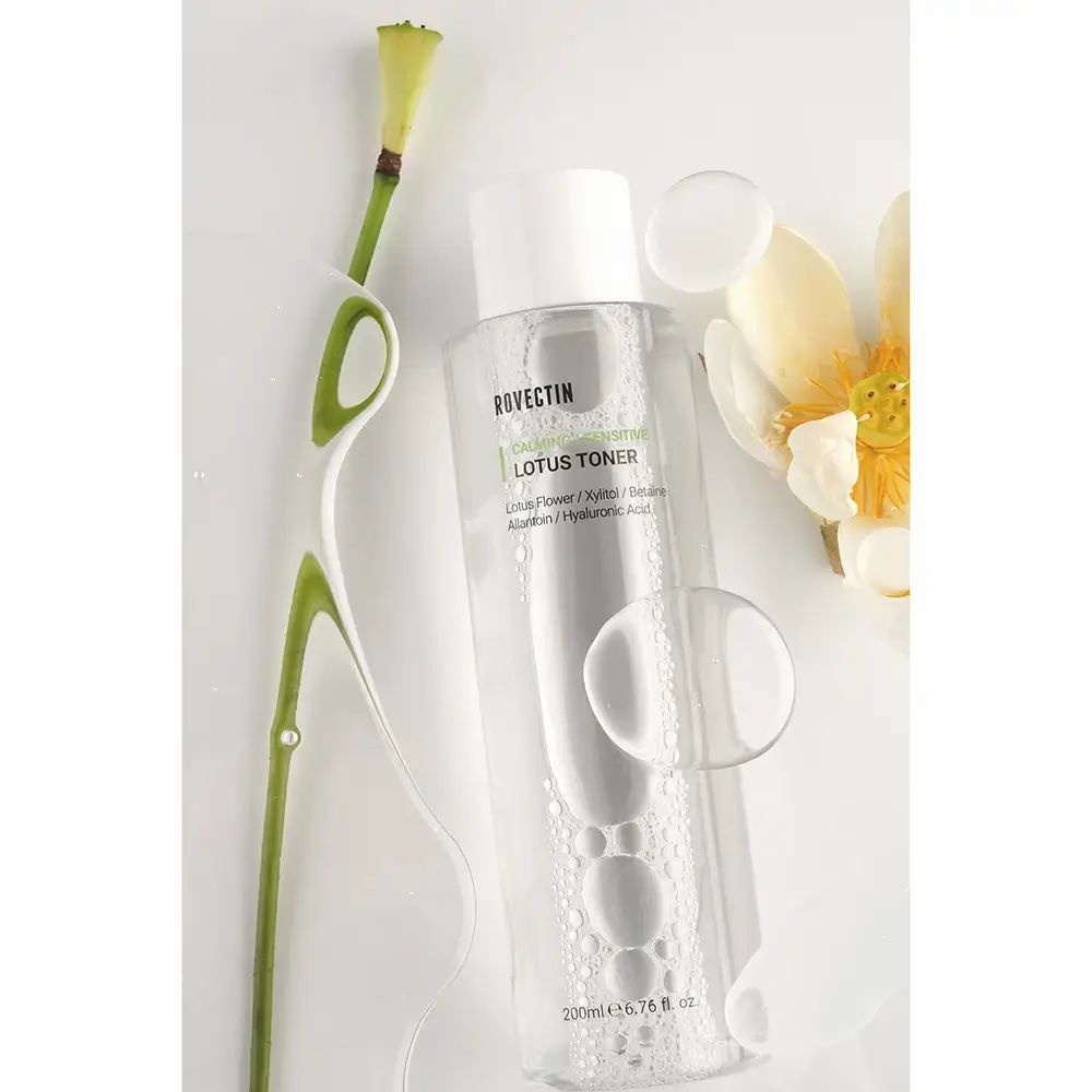 Transparente Flasche mit weißem Deckel. Aufschrift: ROVECTIN Calming Lotus Toner. Mit Lotusblüte und Stiel. Unten: 200ml 6.76 fl. oz.