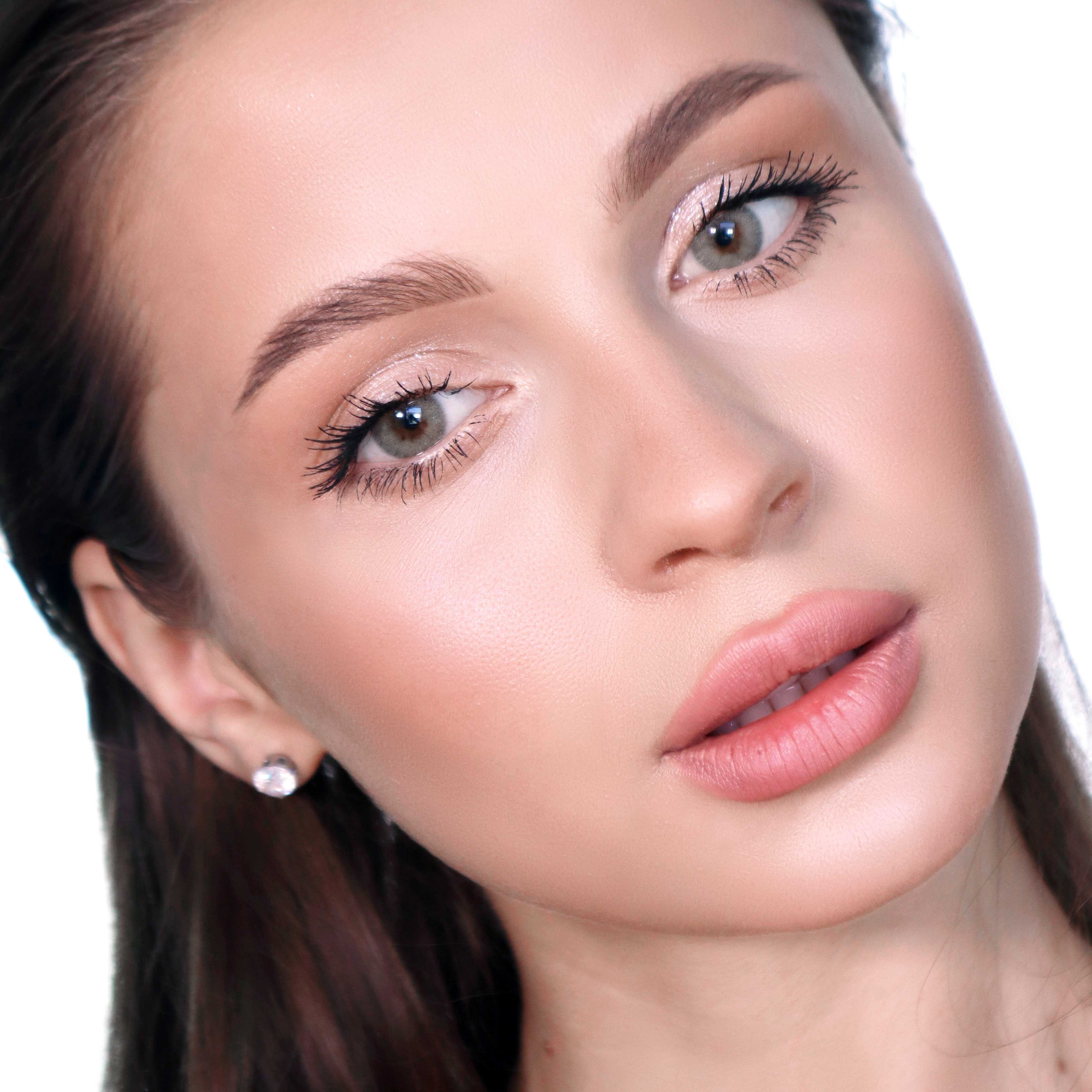 Nahaufnahme eines Gesichts mit silbergrauen Augen. Die Person hat helle Haut und trägt Make-up. Ein Ohrring ist sichtbar.