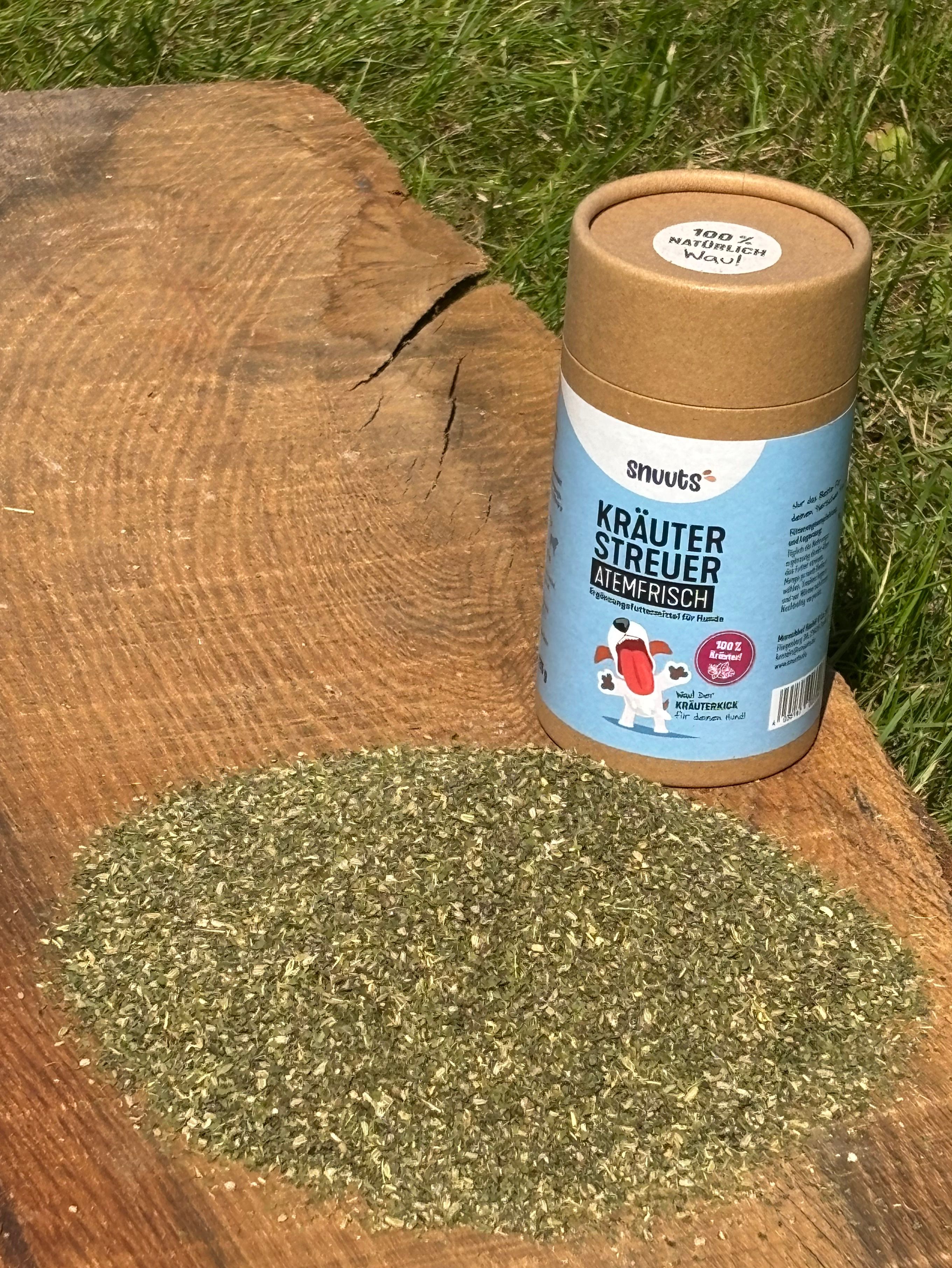 Zylindrische Verpackung und Kräuterstreuer. Aufschrift: snuuts Kräuterstreuer Atemfrisch. Kräuter auf Holzuntergrund verstreut.