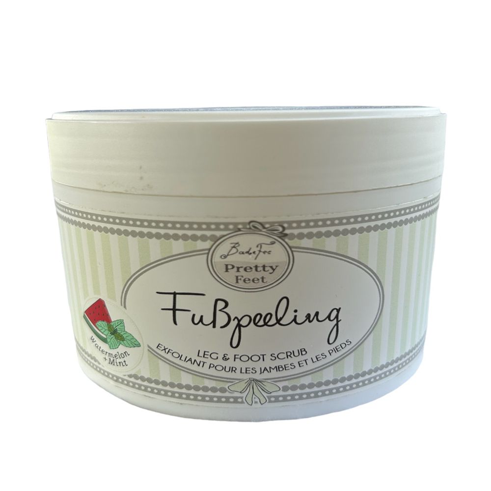 Runder Behälter mit Badefee Fußpeeling. Aufschrift: Fußpeeling, Leg & Foot Scrub. Abbildung von Wassermelone und Minze.