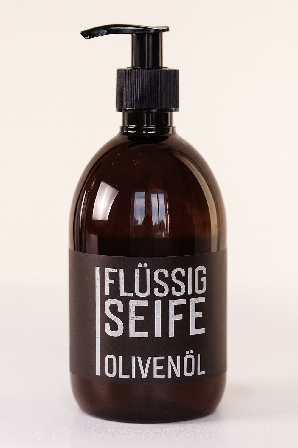 Braune Flasche mit schwarzem Pumpkopf. Aufkleber mit weißer Schrift: Flüssig Seife Olivenöl.