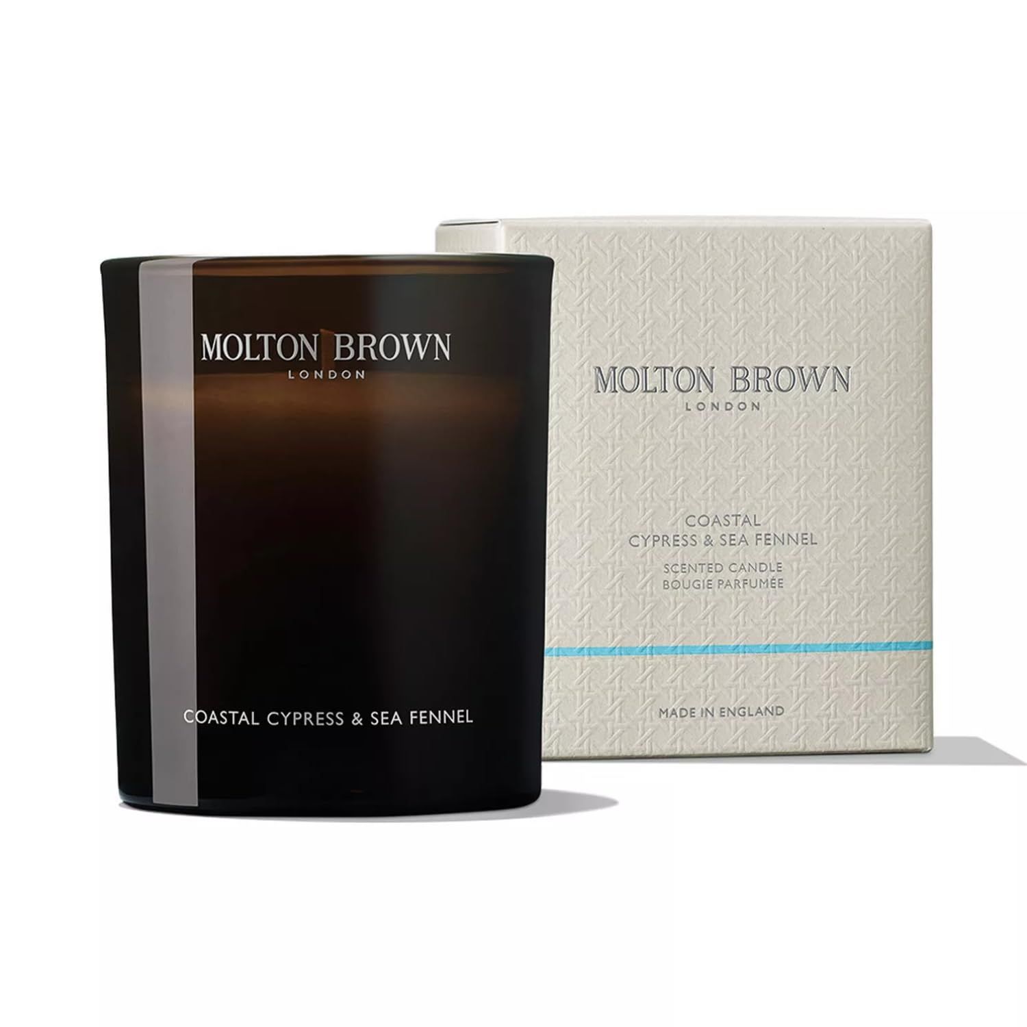 Dunkle Kerze und Verpackung. Aufschrift: Molton Brown, Coastal Cypress & Sea Fennel. Hergestellt in England.