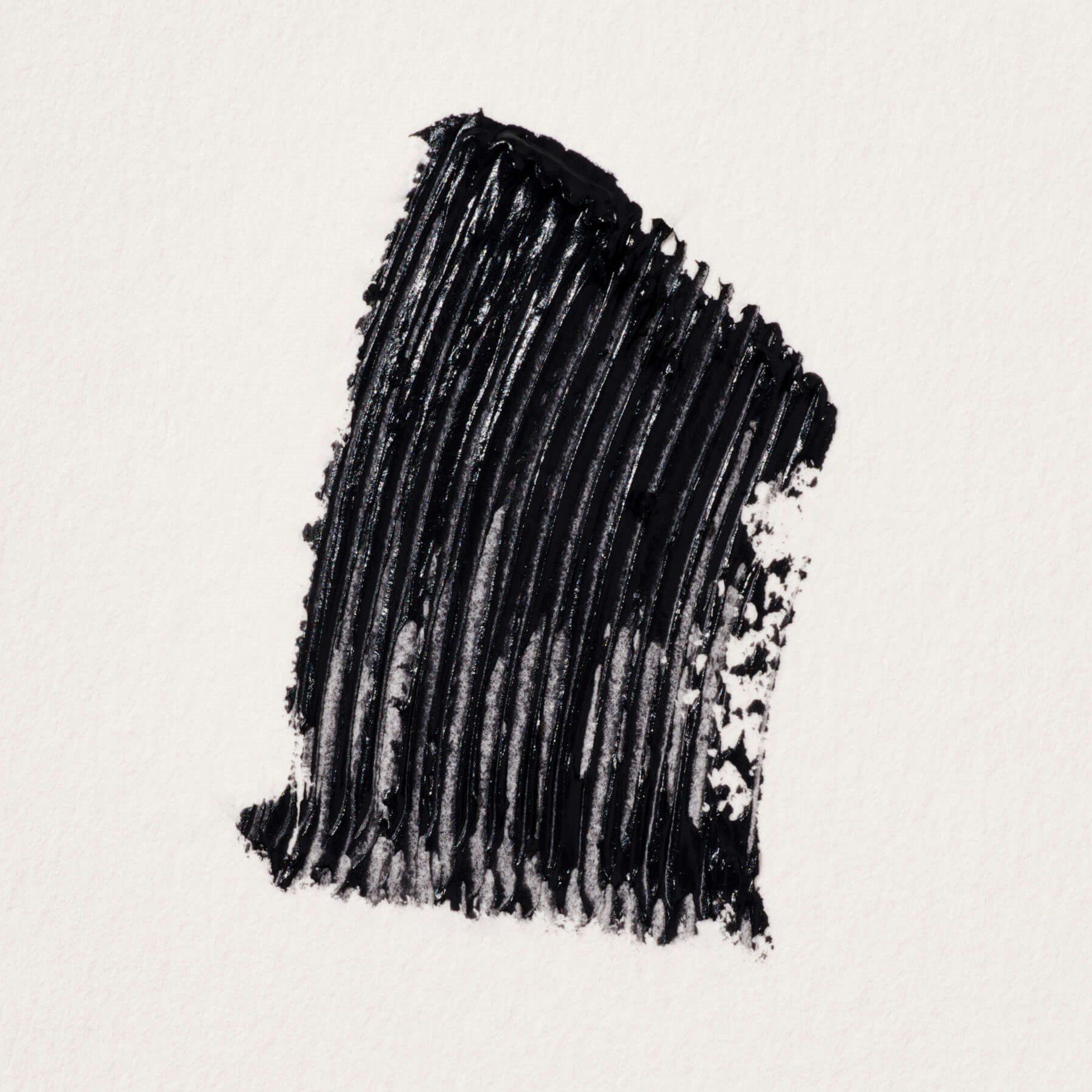Schwarzer Mascara-Abstrich auf weißem Papier. Textur deutlich sichtbar.