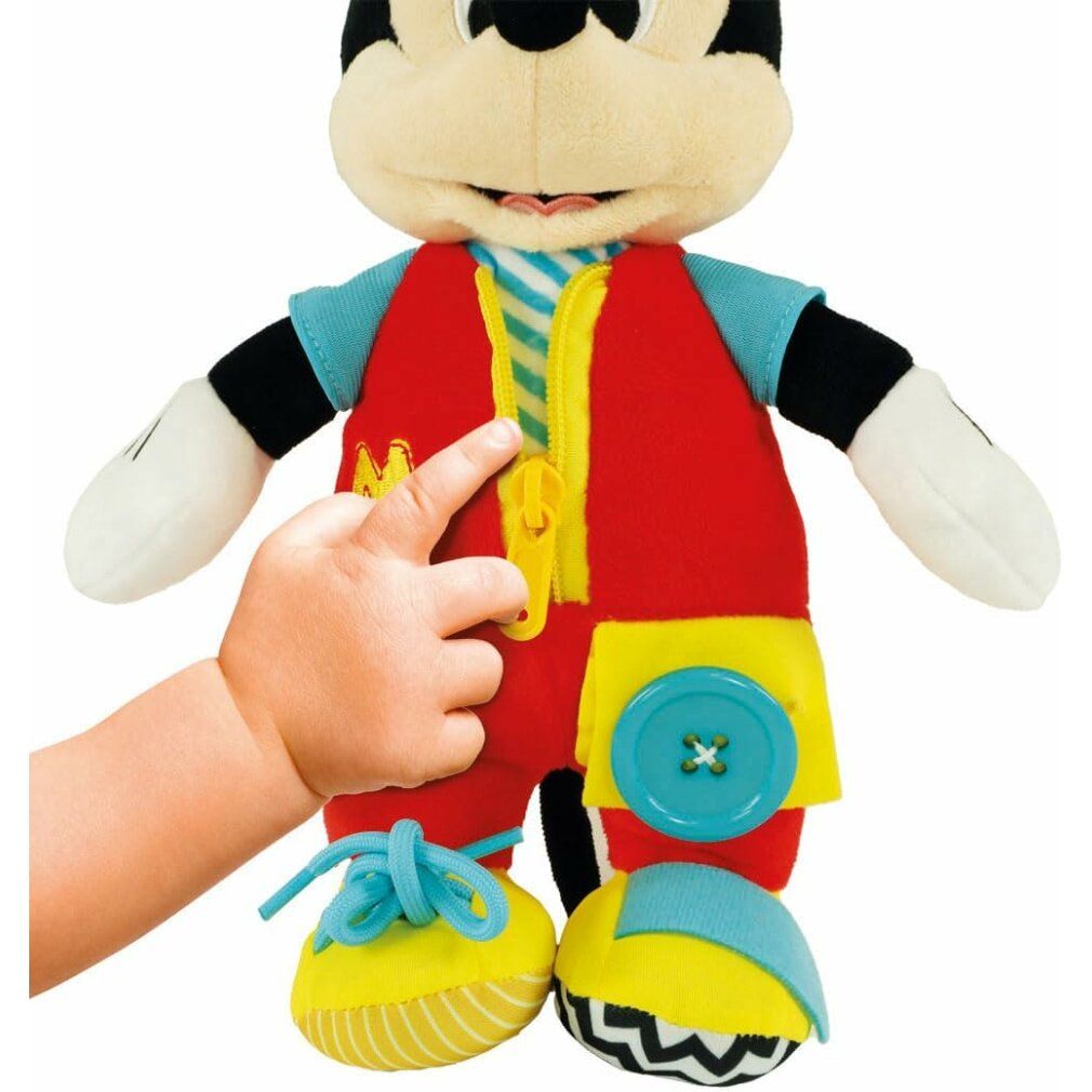 Hand öffnet Reißverschluss an Mickey Mouse Stofftier. Roter Overall mit gelbem Reißverschluss. Blaue Schnürsenkel an gelben Schuhen.