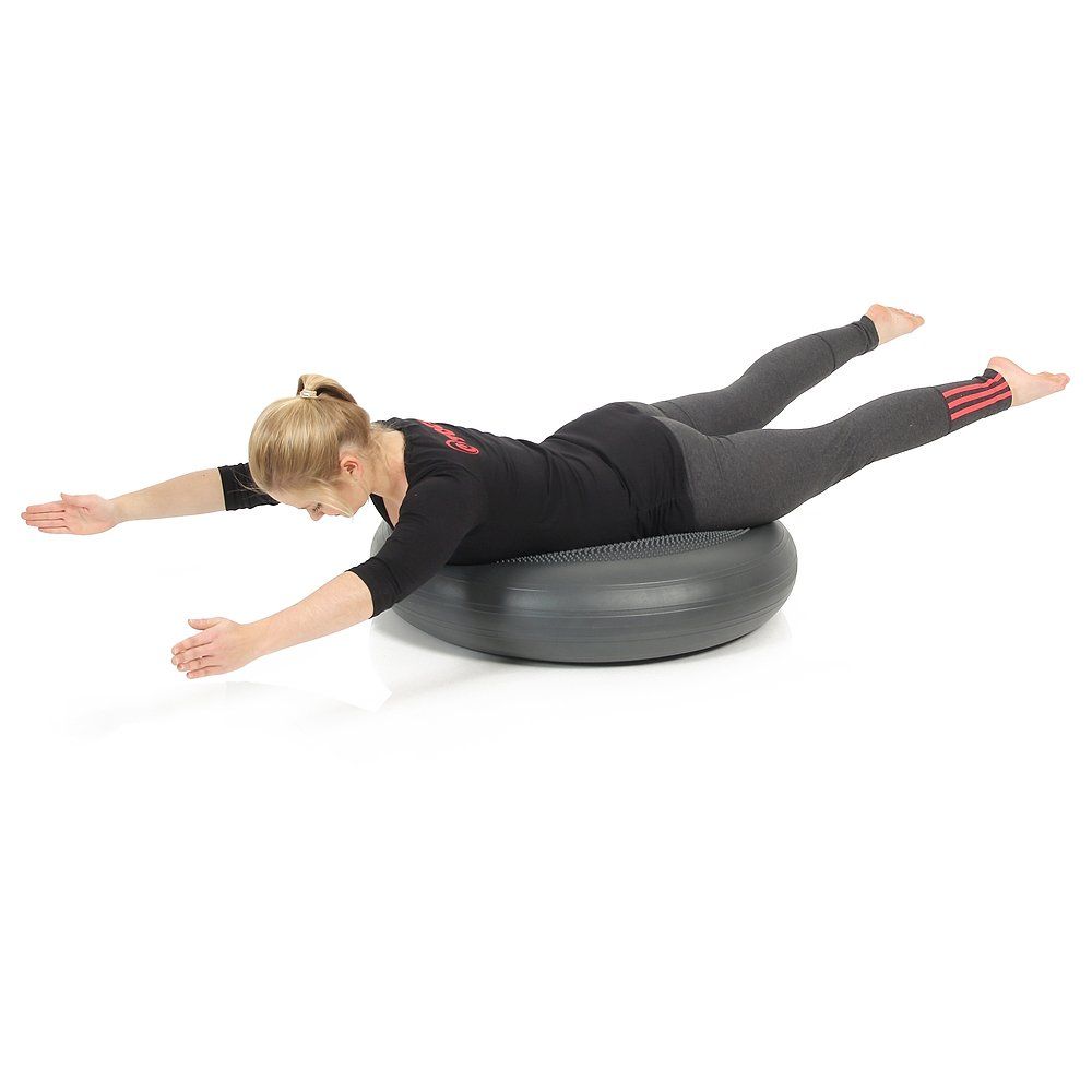 Person liegt auf einem grauen, runden Ballkissen. Arme und Beine ausgestreckt.