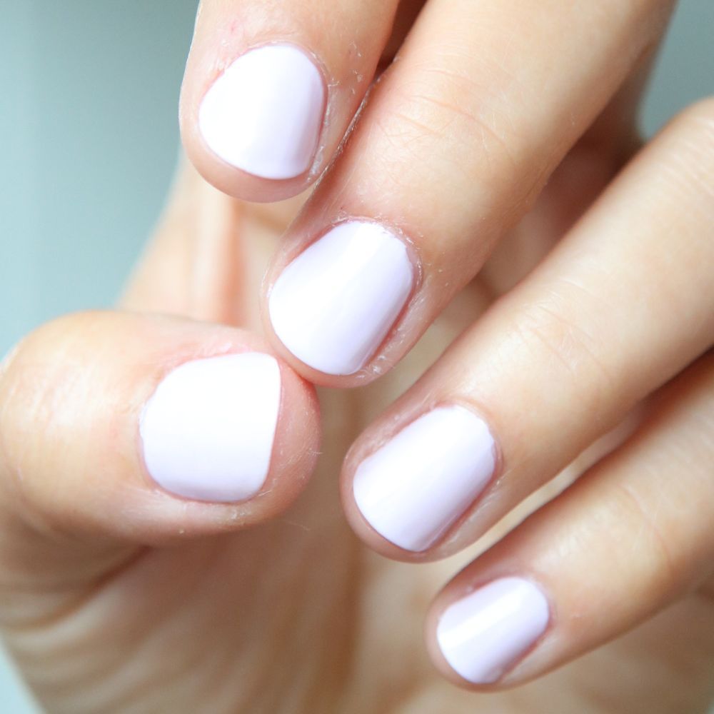 Nahaufnahme von fünf Fingern mit helllila Nagellack. Die Nägel sind kurz und lackiert.