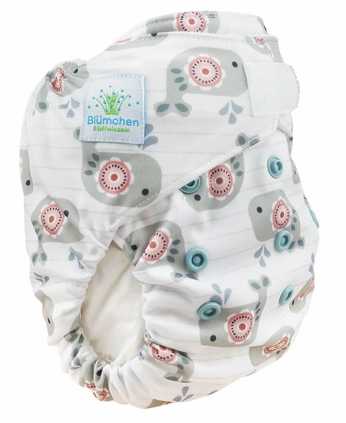Geöffnete Stoffwindel mit Wal-Muster. Innenfutter sichtbar. Logo "Blümchen" auf einem Etikett.