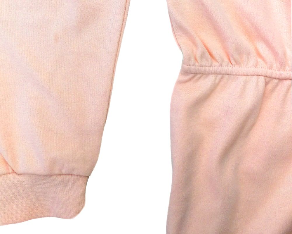 Detailansicht des aprikotfarbenen Pflegeoveralls. Elastischer Bund. Naht zwischen Oberteil und Hose.