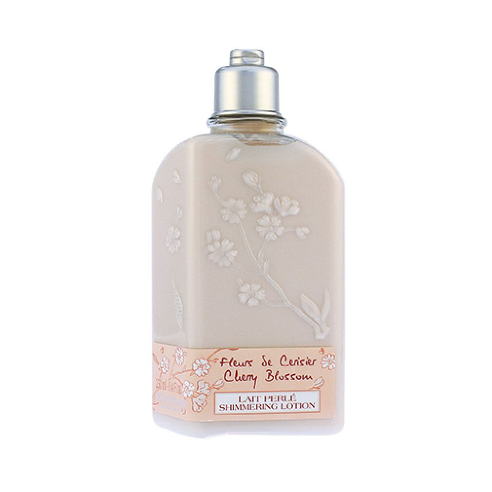 Beige Flasche mit Blütenrelief und silbernem Verschluss. Aufschrift: Fleur de Cerisier Cherry Blossom, Lait Perlé Shimmering Lotion.