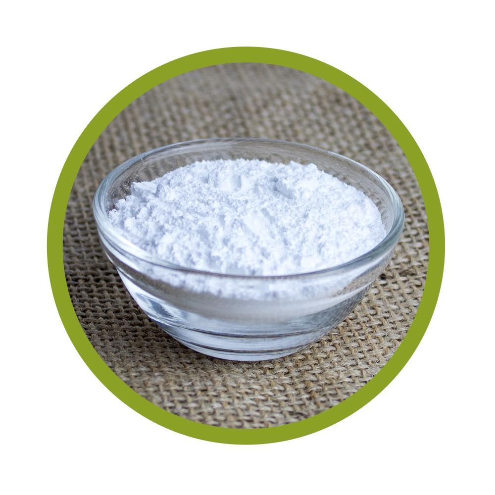 Runde, transparente Glasschale gefüllt mit weißem Pulver. Auf grobem, beigen Stoff platziert.