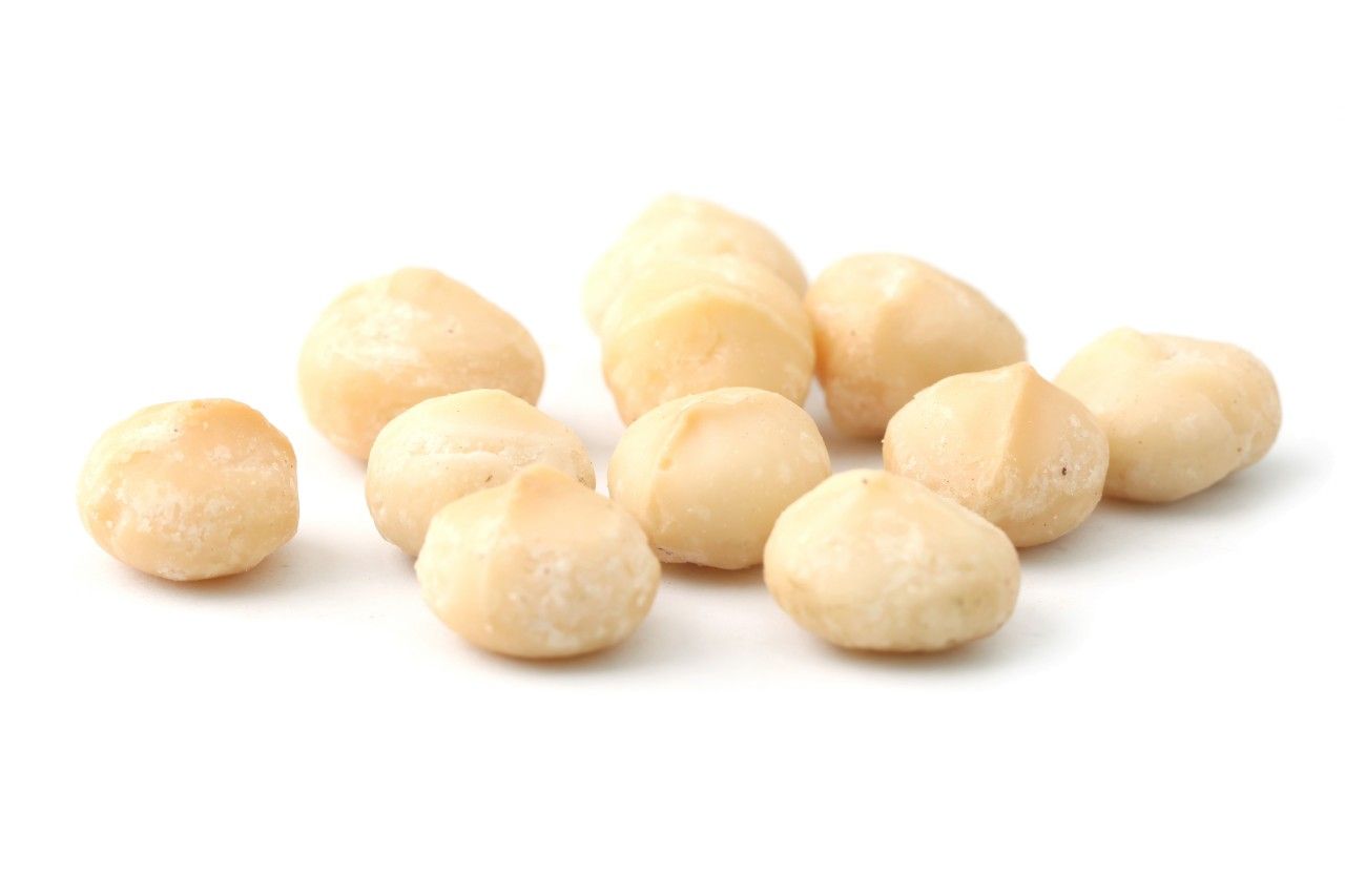 Eine Gruppe von hellbraunen Macadamianusskernen auf weißem Hintergrund. Die Nüsse sind rundlich und haben eine glatte Oberfläche.