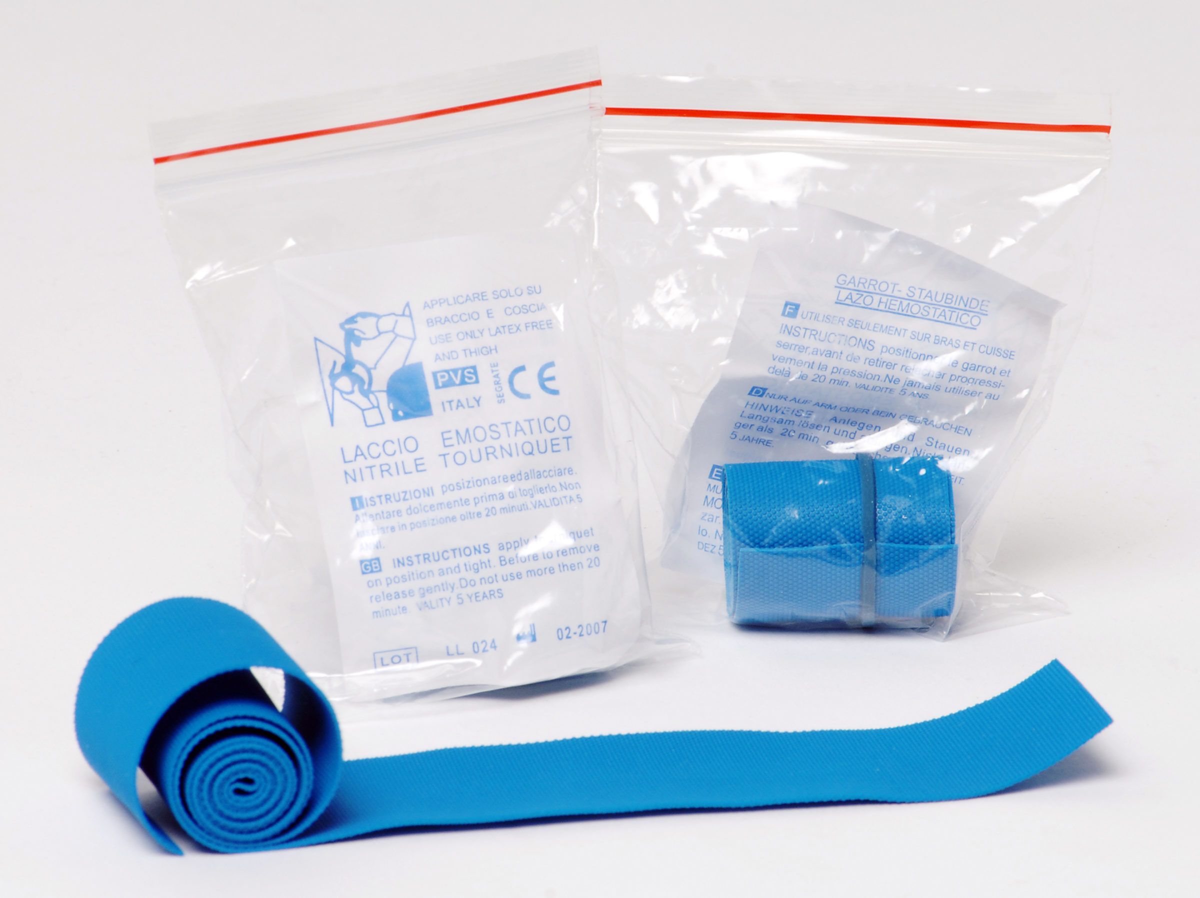 Blaues Laccio emostatico, teilweise abgerollt, neben Verpackungen mit Text.