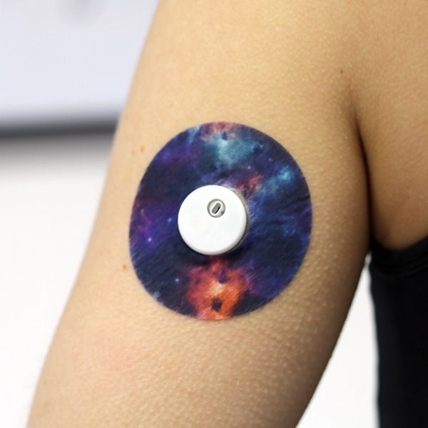 Arm mit rundem Pflaster mit Weltraum-Design und weißem Sensor in der Mitte. Wasserdicht und atmungsaktiv.