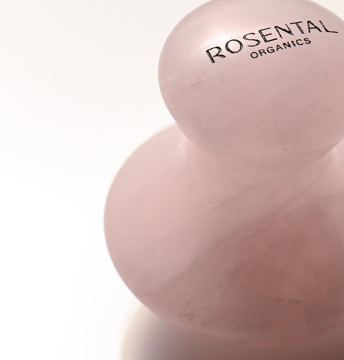 Nahaufnahme eines Rosental Organics Eye Flowies aus rosa Rosenquarz. Logo sichtbar.
