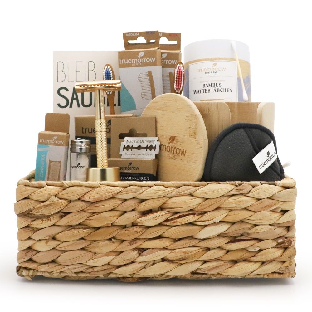 Geschenkset in einem geflochtenen Korb. Enthält Rasierer, Abschminkpads, Zahnbürsten, Bambus-Wattestäbchen und weitere Produkte.