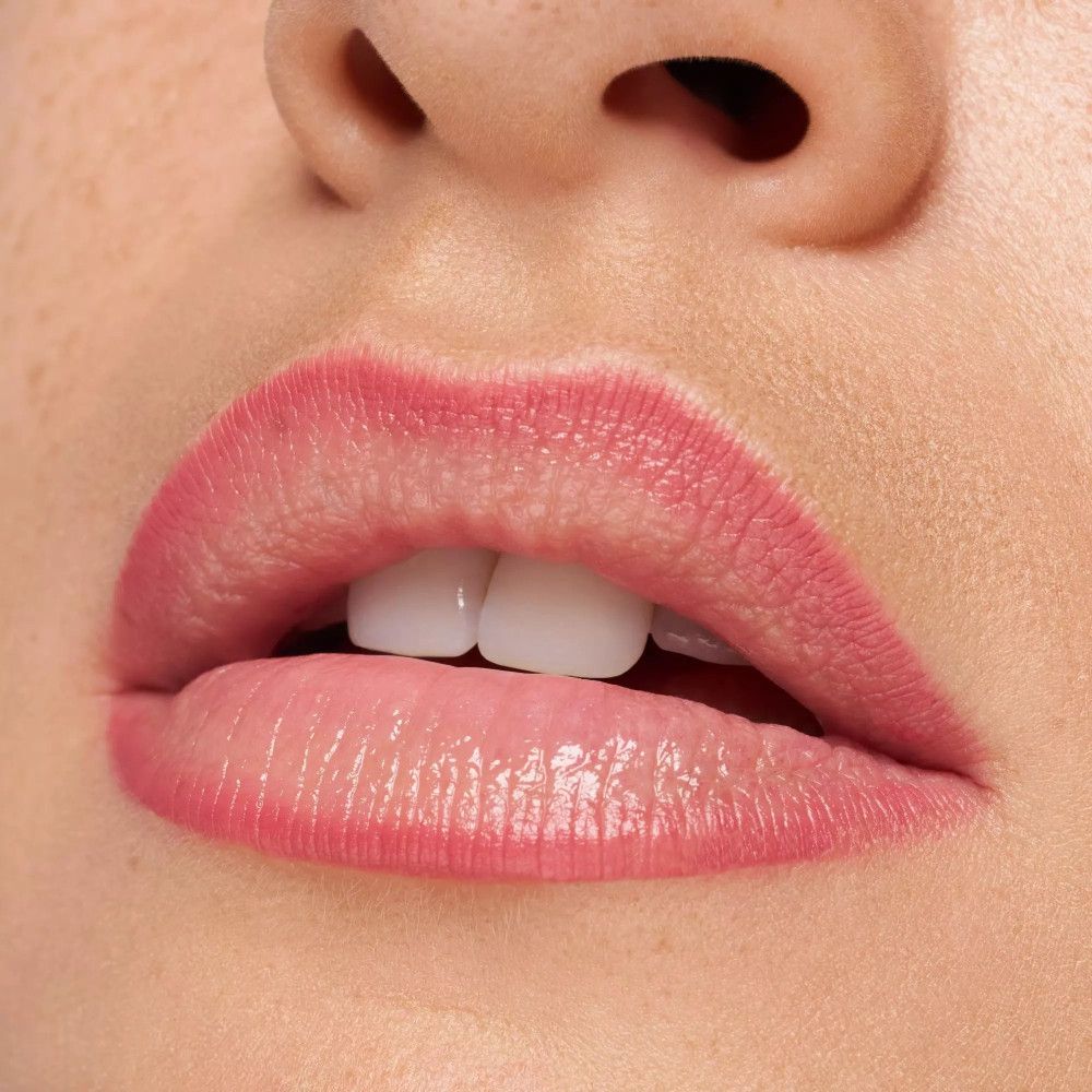 Nahaufnahme von Lippen mit rosa Lippenstift. Offener Mund, Zähne sichtbar.