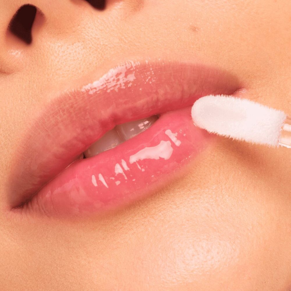 Nahaufnahme von Lippen, die mit Lipgloss bestrichen werden. Der Applikator ist sichtbar.