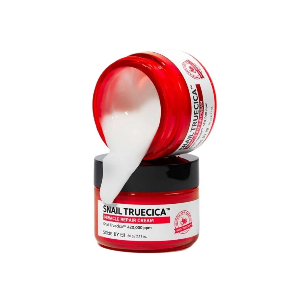 SOMEBYMI Snail Truecica Miracle Repair Cream: Geöffnete rote Dose, weiße Creme fließt heraus auf eine zweite Dose.