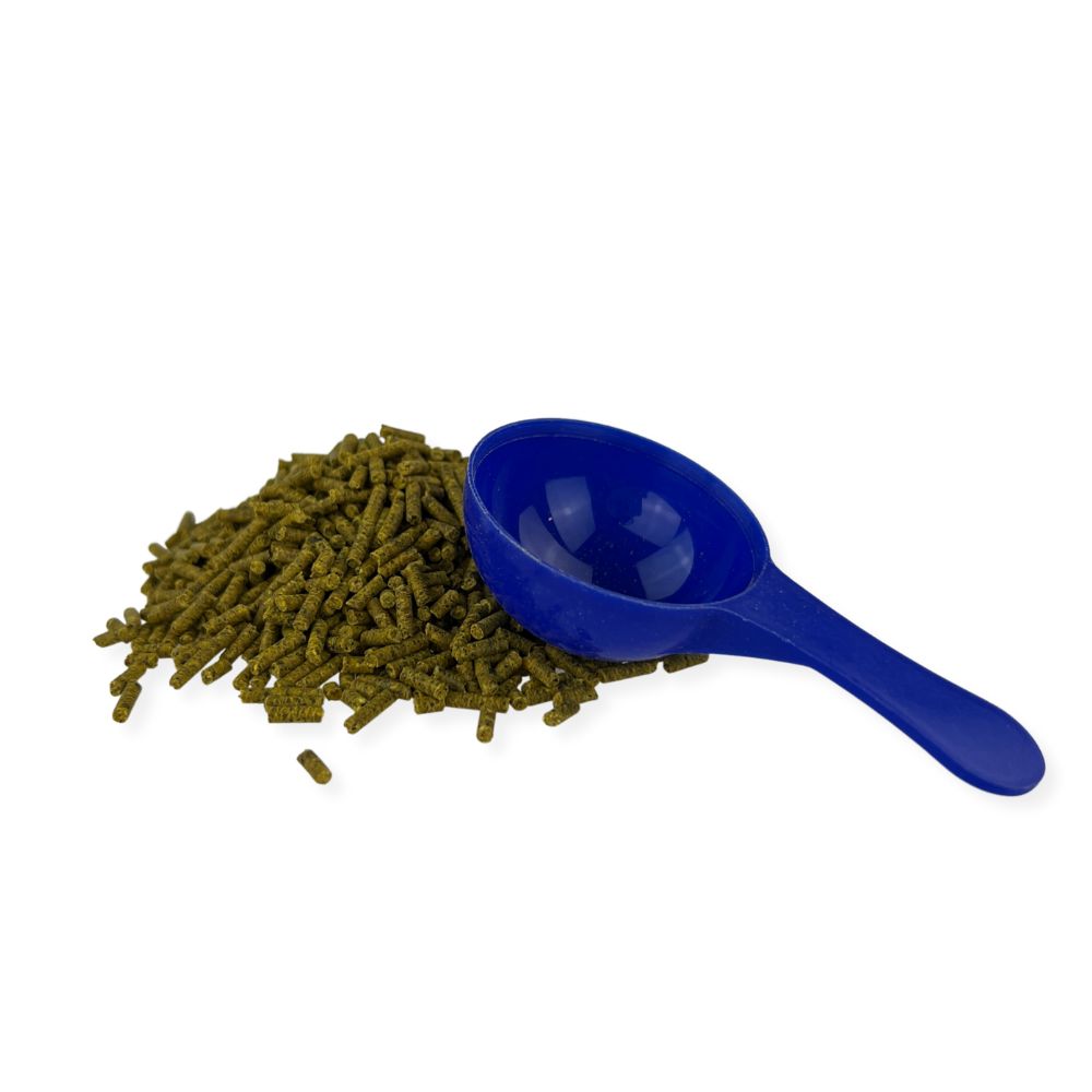 Haufen grüner Pellets mit blauem Messlöffel. Das Produkt ist ein Nahrungsergänzungsmittel für Hunde und Katzen.