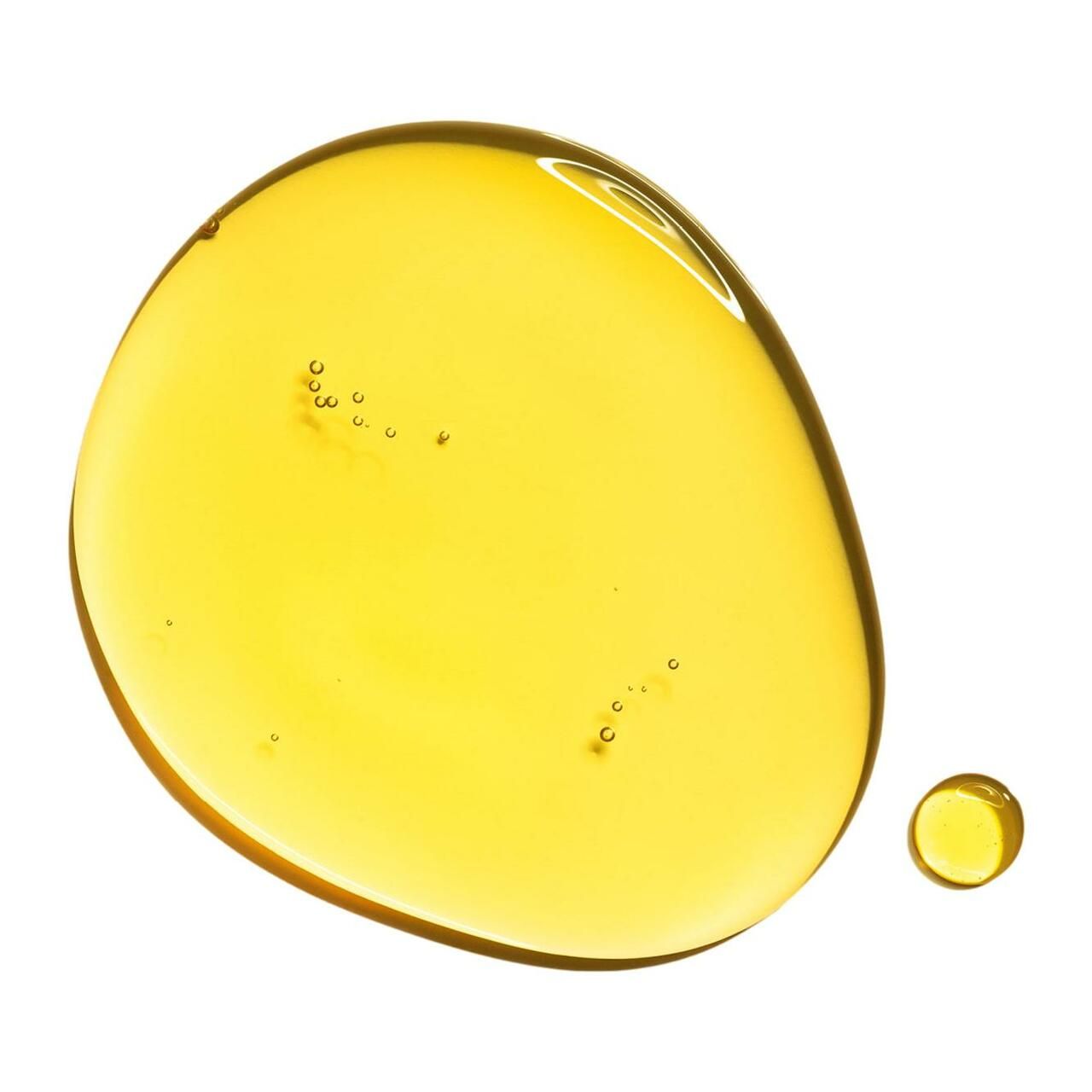 Ein Tropfen goldgelbes Öl mit kleinen Luftblasen auf weißem Hintergrund.