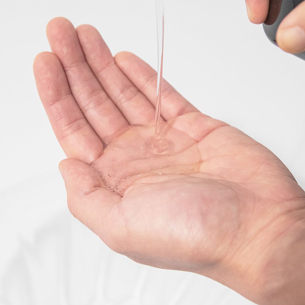 Shampoo wird aus einem Spender in eine Handfläche gegeben.